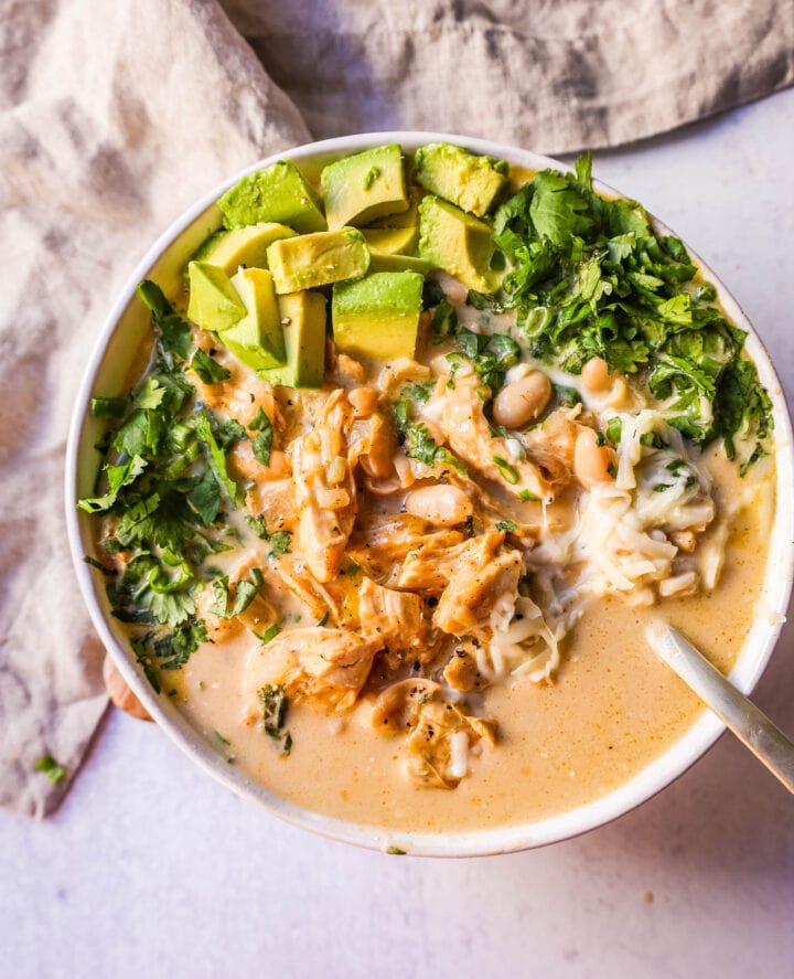 The Best White Chicken Chili Recipe made with shredded chicken, jalapeno, onion, spices, in a creamy chicken broth with salsa verde, cream cheese, white beans, shredded cheese, and fresh cilantro. The perfect creamy white chicken chili recipe!