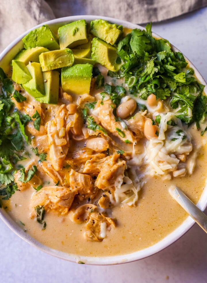 The Best White Chicken Chili Recipe made with shredded chicken, jalapeno, onion, spices, in a creamy chicken broth with salsa verde, cream cheese, white beans, shredded cheese, and fresh cilantro. The perfect creamy white chicken chili recipe!