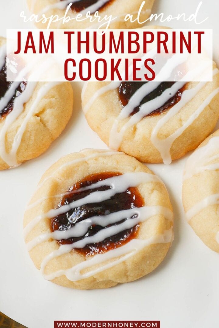 Raspberry Almond Jam Thumbprint Cookies are buttery shortbread cookies made with only butter, sugar, flour, and almond extract, topped with jam, and baked until soft and topped with homemade vanilla or almond glaze. A festive and delicious Christmas cookie recipe!