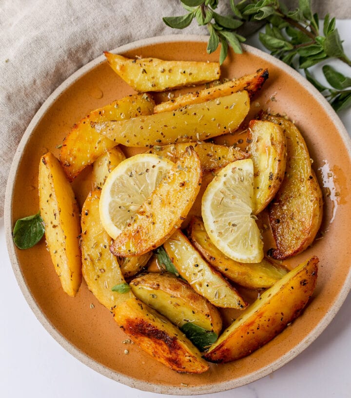 These Greek Roasted Potatoes are infused with extra-virgin olive oil, lemon juice, garlic, oregano, spices, and chicken broth which makes the creamiest roasted potatoes full of Greek flavor.