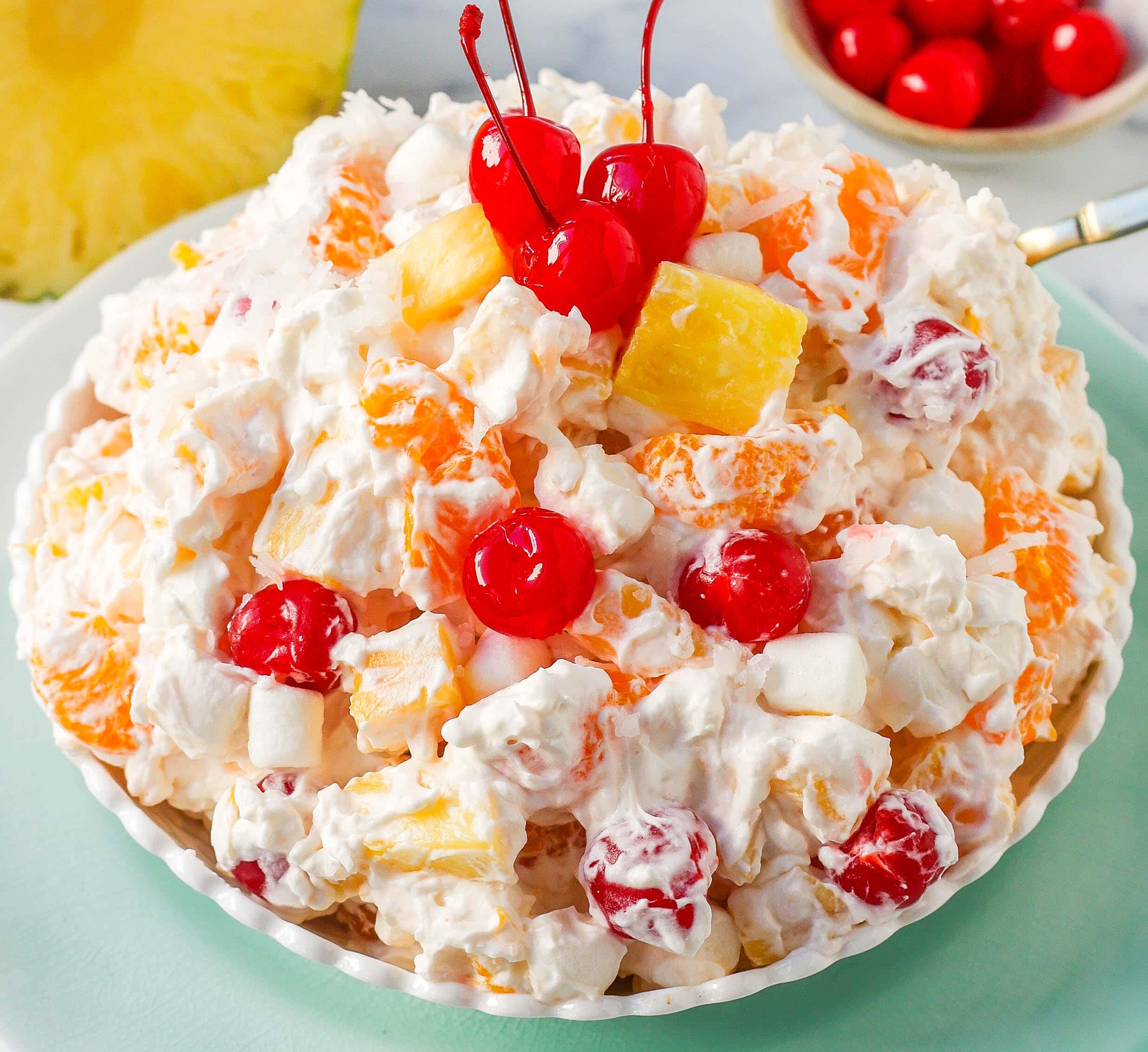 The Best Ambrosia Salad is a fluffy salad made with fresh pineapple, mandarin oranges, maraschino cherries, coconut, marshmallows, fresh whipped cream, a touch of sour cream, and sugar. This is a nostalgic, classic side dish or dessert recipe.