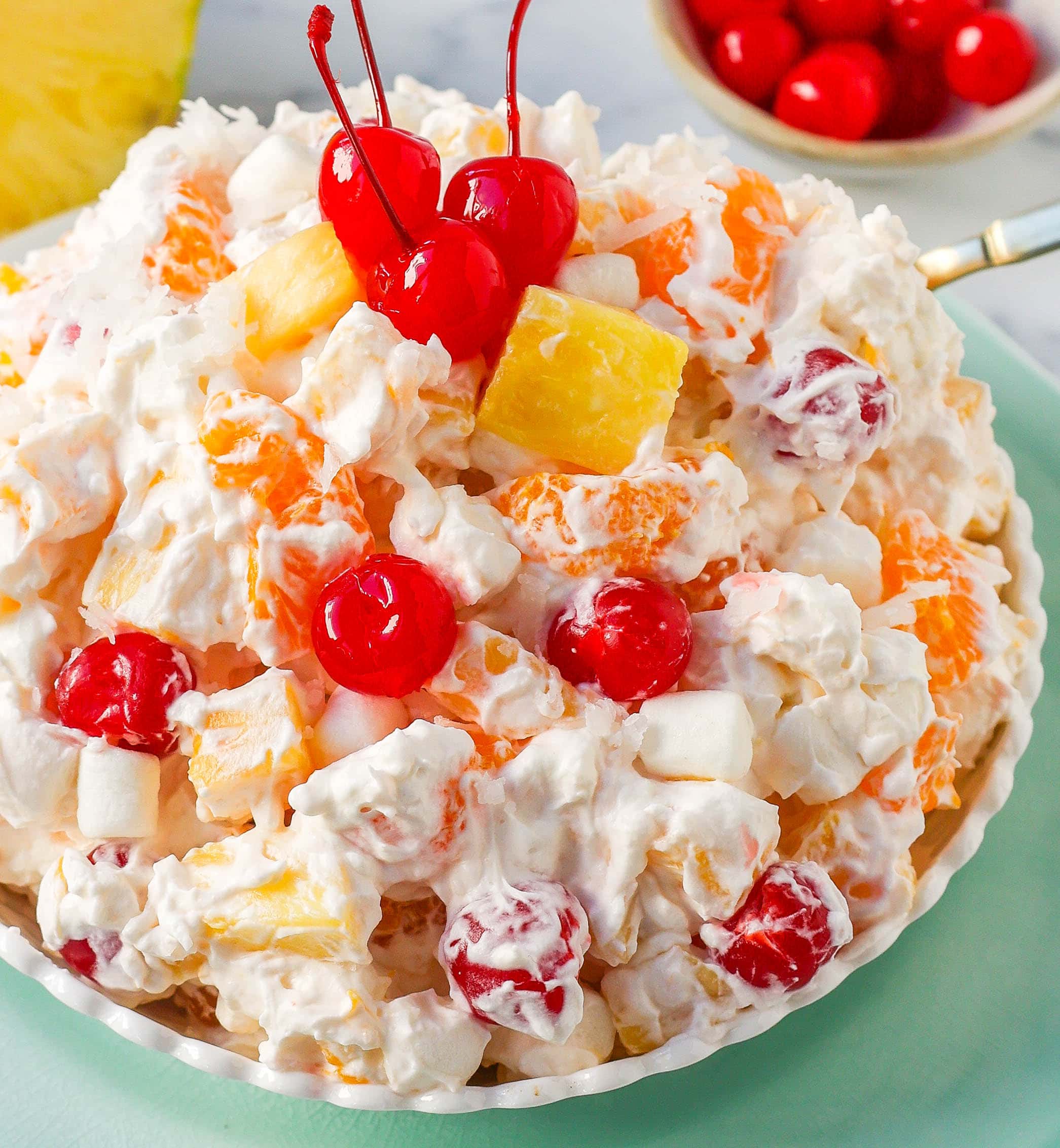 The Best Ambrosia Salad is a fluffy salad made with fresh pineapple, mandarin oranges, maraschino cherries, coconut, marshmallows, fresh whipped cream, a touch of sour cream, and sugar. This is a nostalgic, classic side dish or dessert recipe.