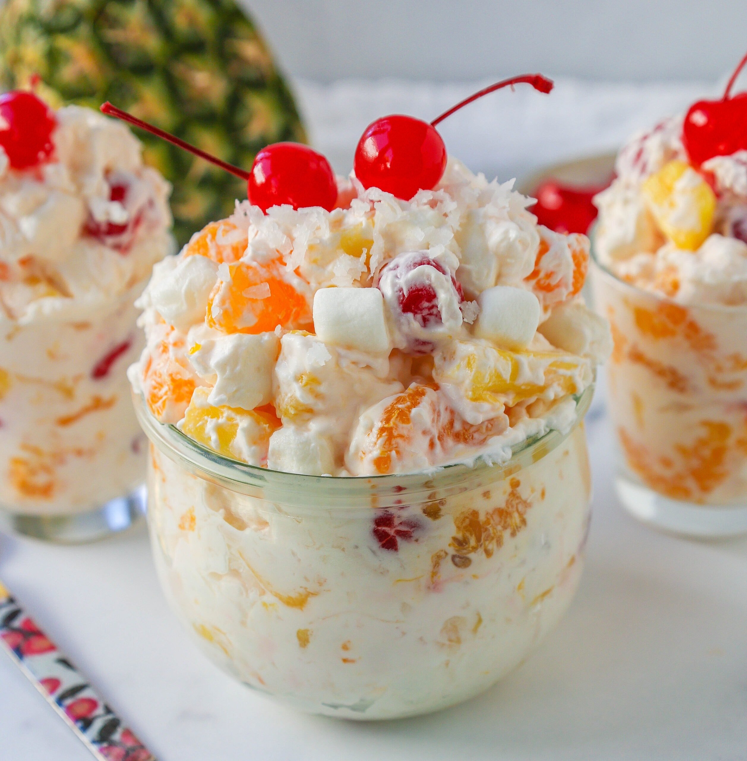 The Best Ambrosia Salad is a fluffy salad made with fresh pineapple, mandarin oranges, maraschino cherries, coconut, marshmallows, fresh whipped cream, a touch of sour cream, and sugar. This is a nostalgic, classic side dish or dessert recipe.