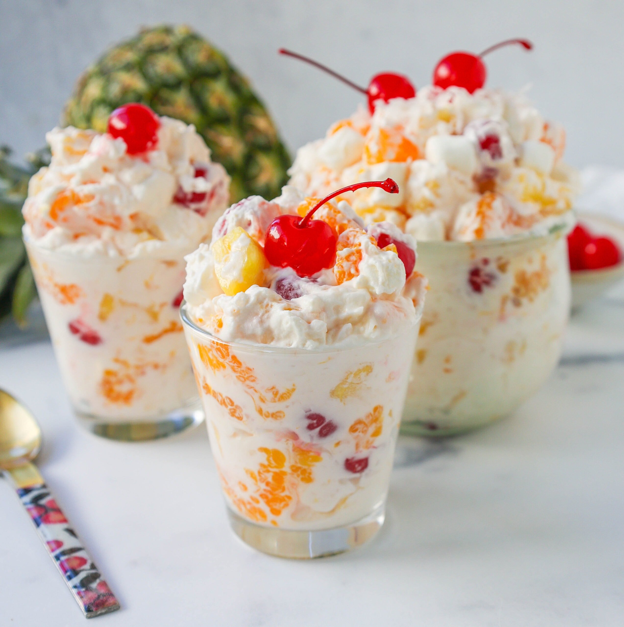 The Best Ambrosia Salad is a fluffy salad made with fresh pineapple, mandarin oranges, maraschino cherries, coconut, marshmallows, fresh whipped cream, a touch of sour cream, and sugar. This is a nostalgic, classic side dish or dessert recipe.