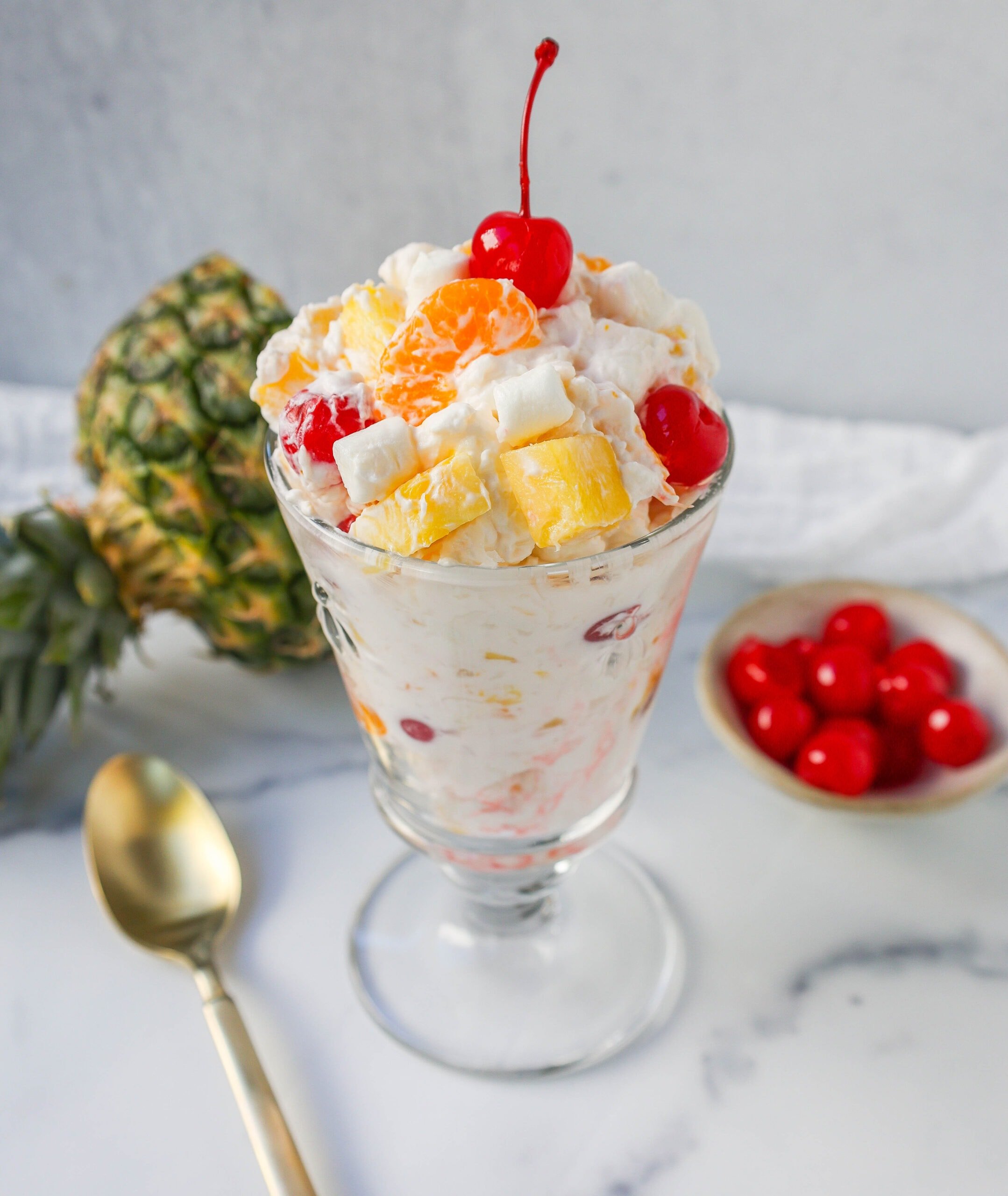 The Best Ambrosia Salad is a fluffy salad made with fresh pineapple, mandarin oranges, maraschino cherries, coconut, marshmallows, fresh whipped cream, a touch of sour cream, and sugar. This is a nostalgic, classic side dish or dessert recipe.