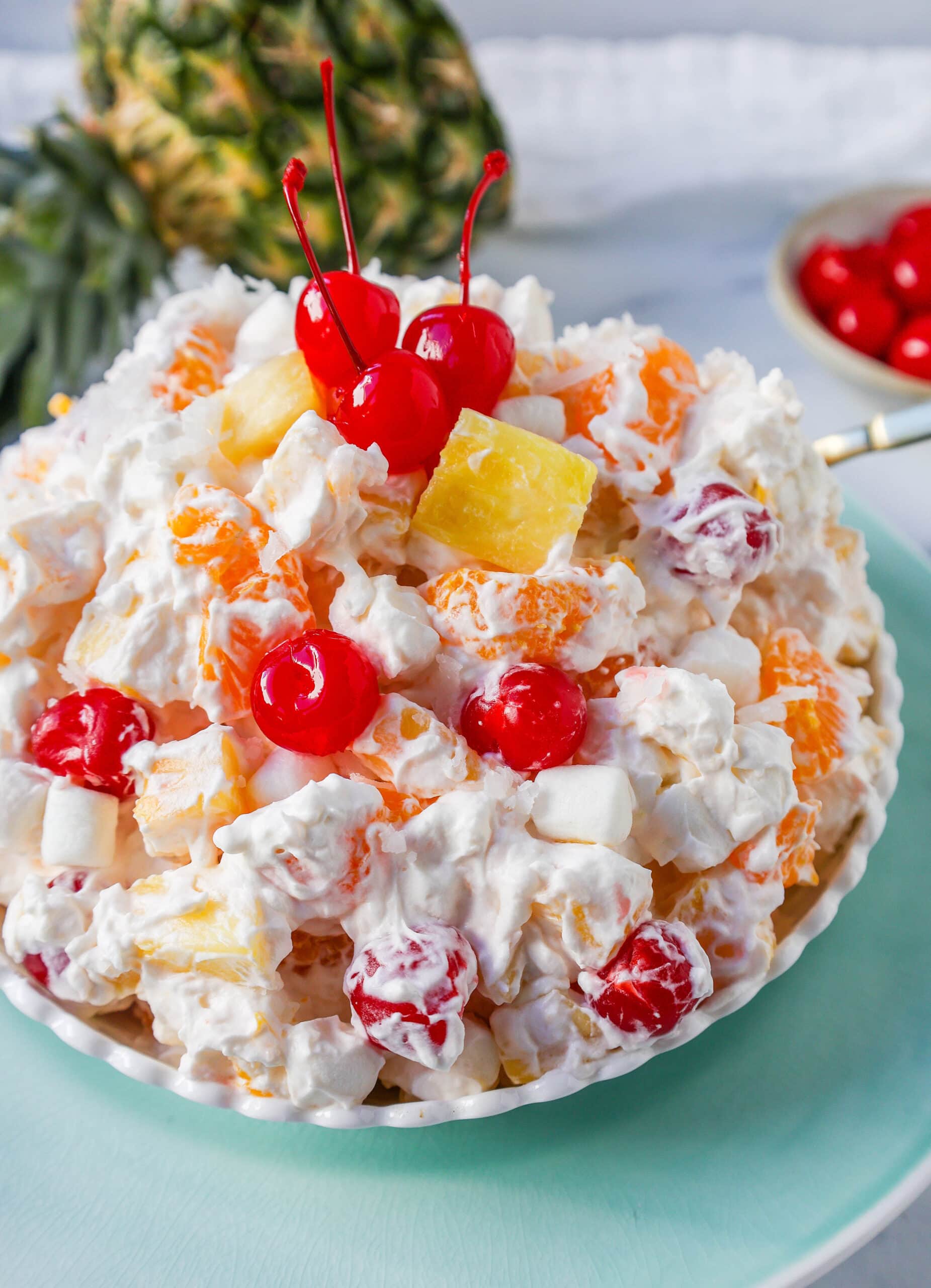 The Best Ambrosia Salad is a fluffy salad made with fresh pineapple, mandarin oranges, maraschino cherries, coconut, marshmallows, fresh whipped cream, a touch of sour cream, and sugar. This is a nostalgic, classic side dish or dessert recipe.