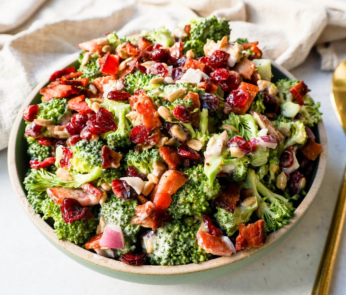 A bowl of homemade broccoli salad. Crunchy, easy broccoli salad with crispy bacon, sweet dried cranberries, onion, and nuts all tossed in a sweet and tangy dressing. Tips for making the best broccoli salad. A classic potluck, BBQ, or summer side dish recipe!