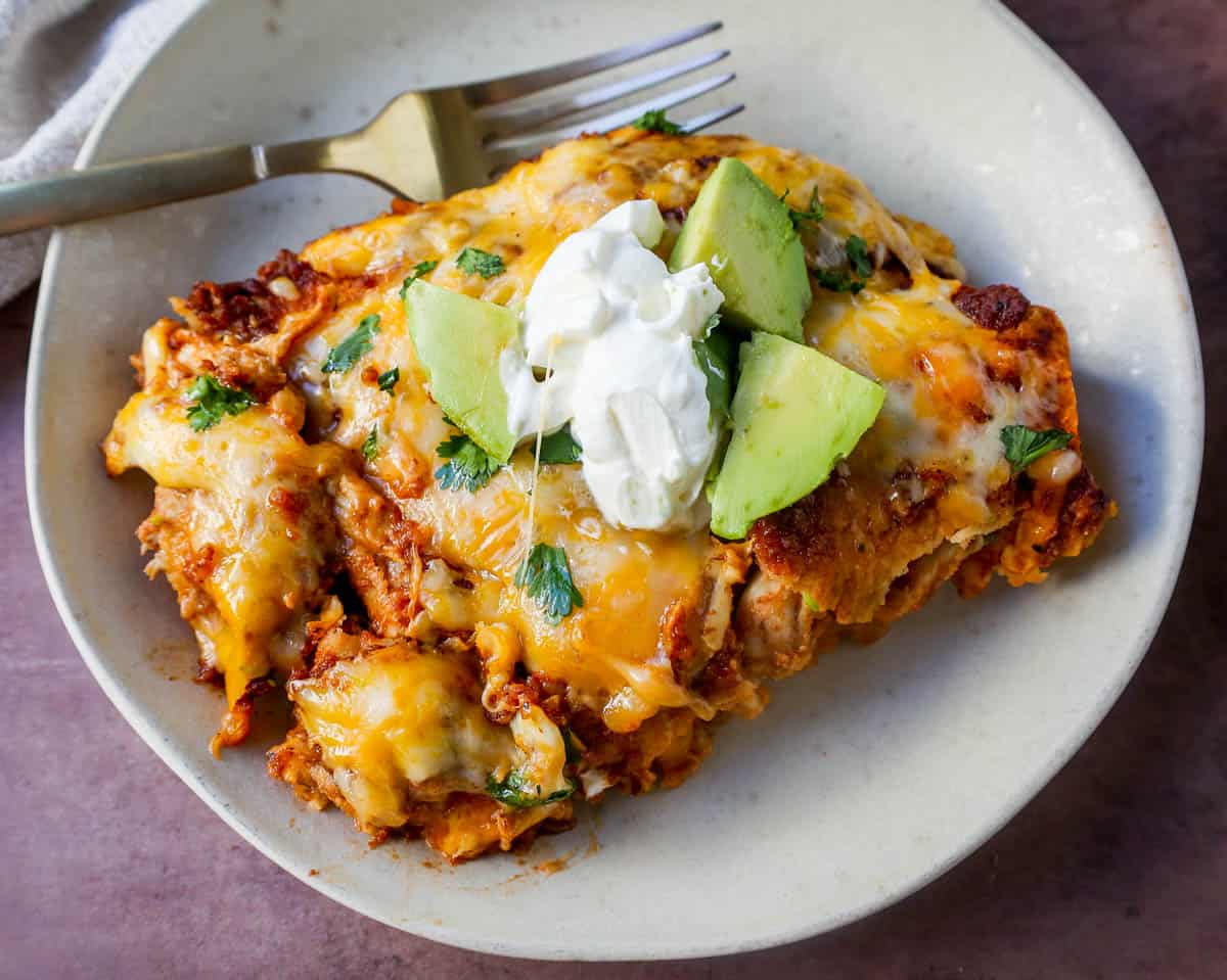 Chicken enchiladas with red sauce are made with soft and savory corn tortillas, shredded chicken, warm and flavorful red sauce from scratch and topped with Mexican crema and cheese.