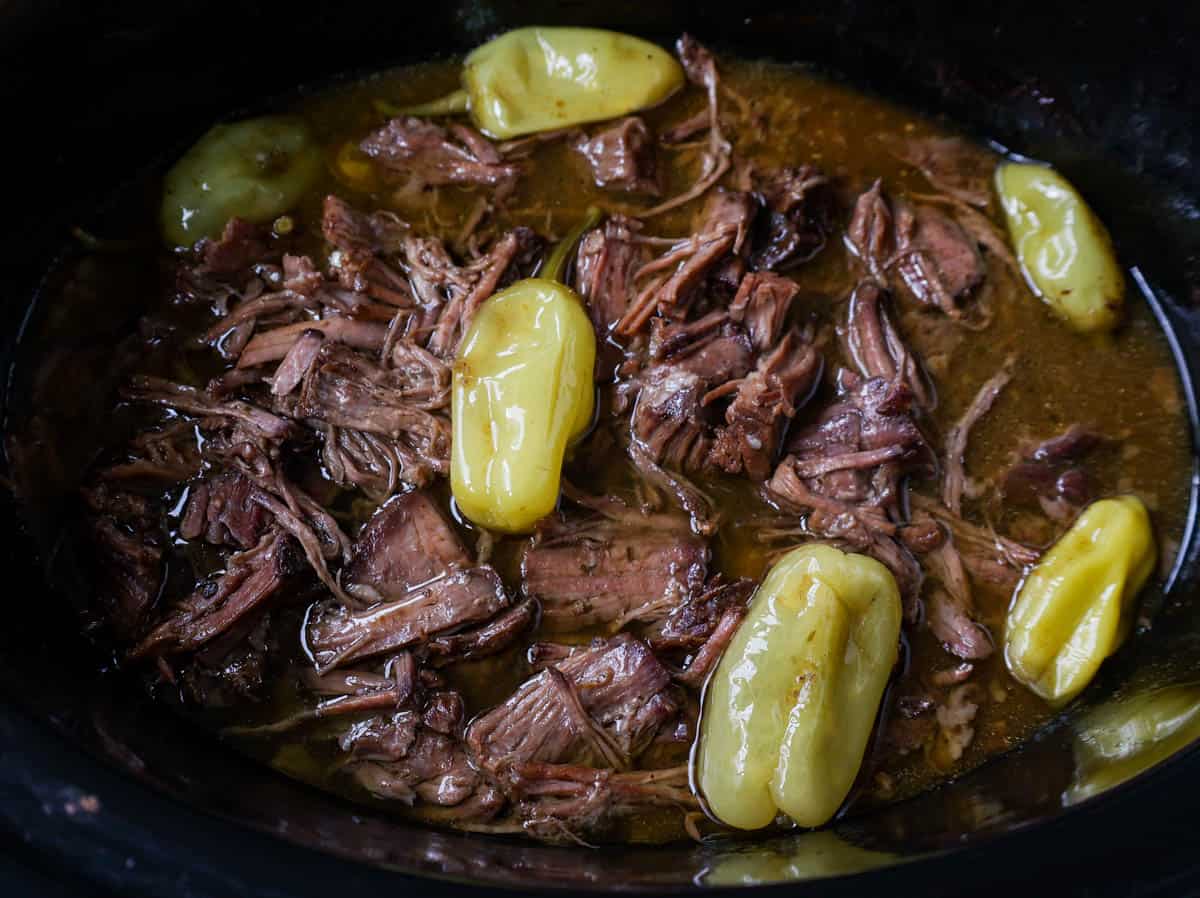 Mississippi Pot Roast cooked low and slow in slow cooker with chuck roast, ranch powder, au jus gravy mix, pepperoncinis, and butter.