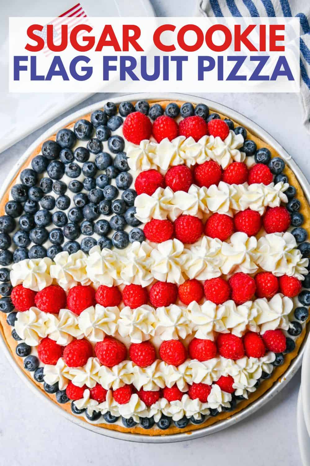 This flag sugar cookie fruit pizza is a festive, delicious, and beautiful patriotic 4th of July dessert featuring a homemade soft sugar cookie crust with a sweet vanilla cream cheese frosting topped with fresh raspberries, blueberries, and homemade whipped cream.