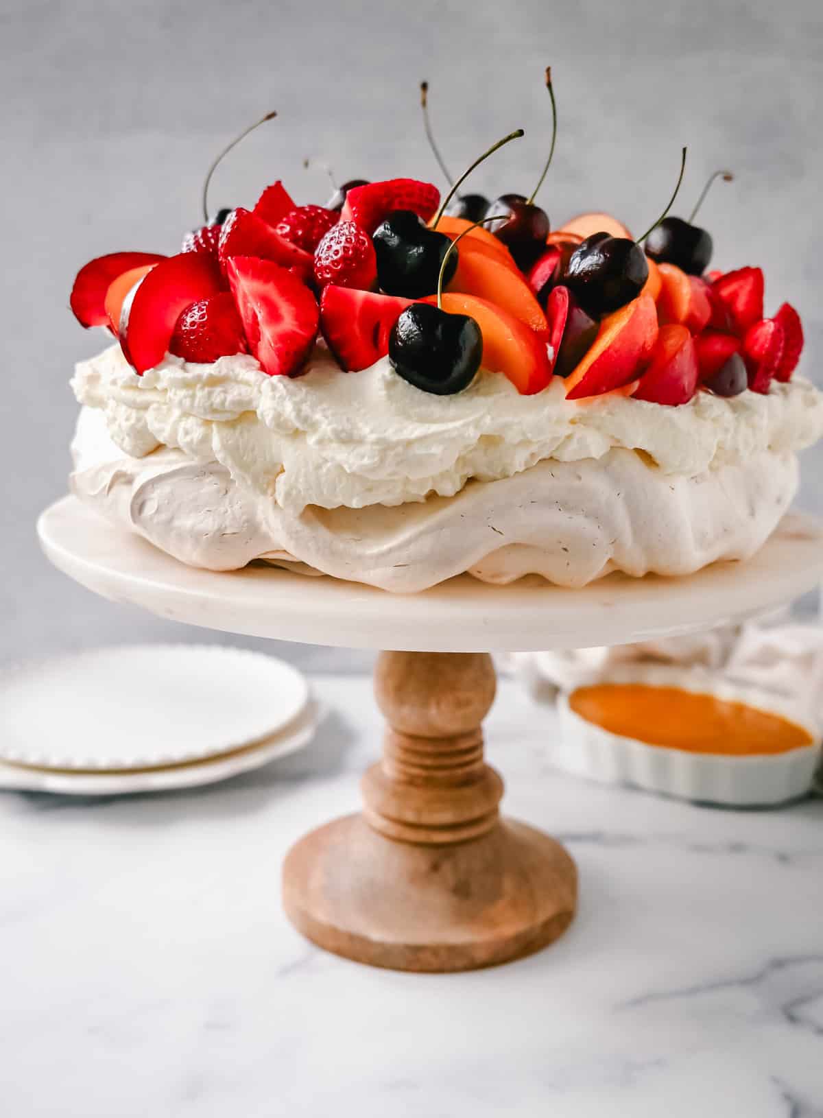 Pavlova. A stunning dessert with a crisp, crunchy outer shell with a soft, marshmallow-like center. Topped with fresh whipped cream and fresh fruit. It is a beautiful and delicious dessert to wow a crowd!