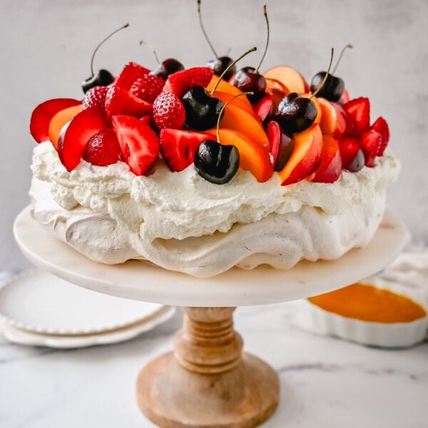 Pavlova. A stunning dessert with a crisp, crunchy outer shell with a soft, marshmallow-like center. Topped with fresh whipped cream and fresh fruit. It is a beautiful and delicious dessert to wow a crowd!