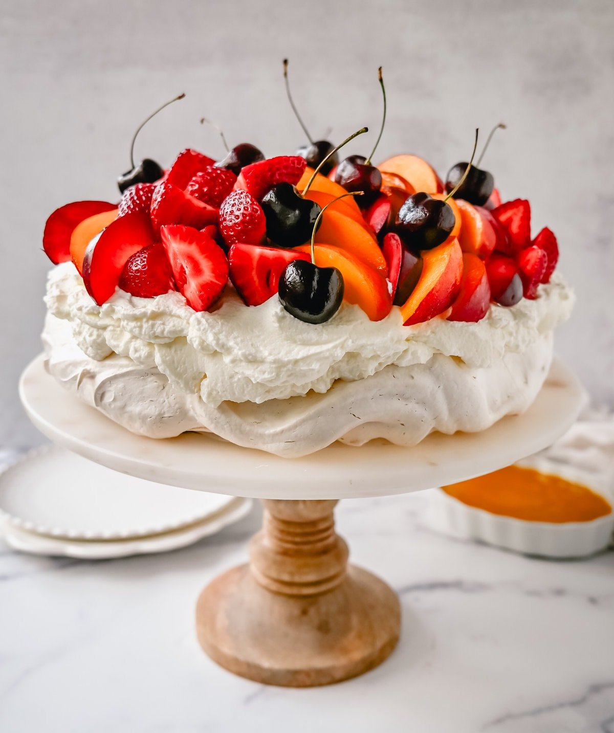 Pavlova. A stunning dessert with a crisp, crunchy outer shell with a soft, marshmallow-like center. Topped with fresh whipped cream and fresh fruit. It is a beautiful and delicious dessert to wow a crowd!