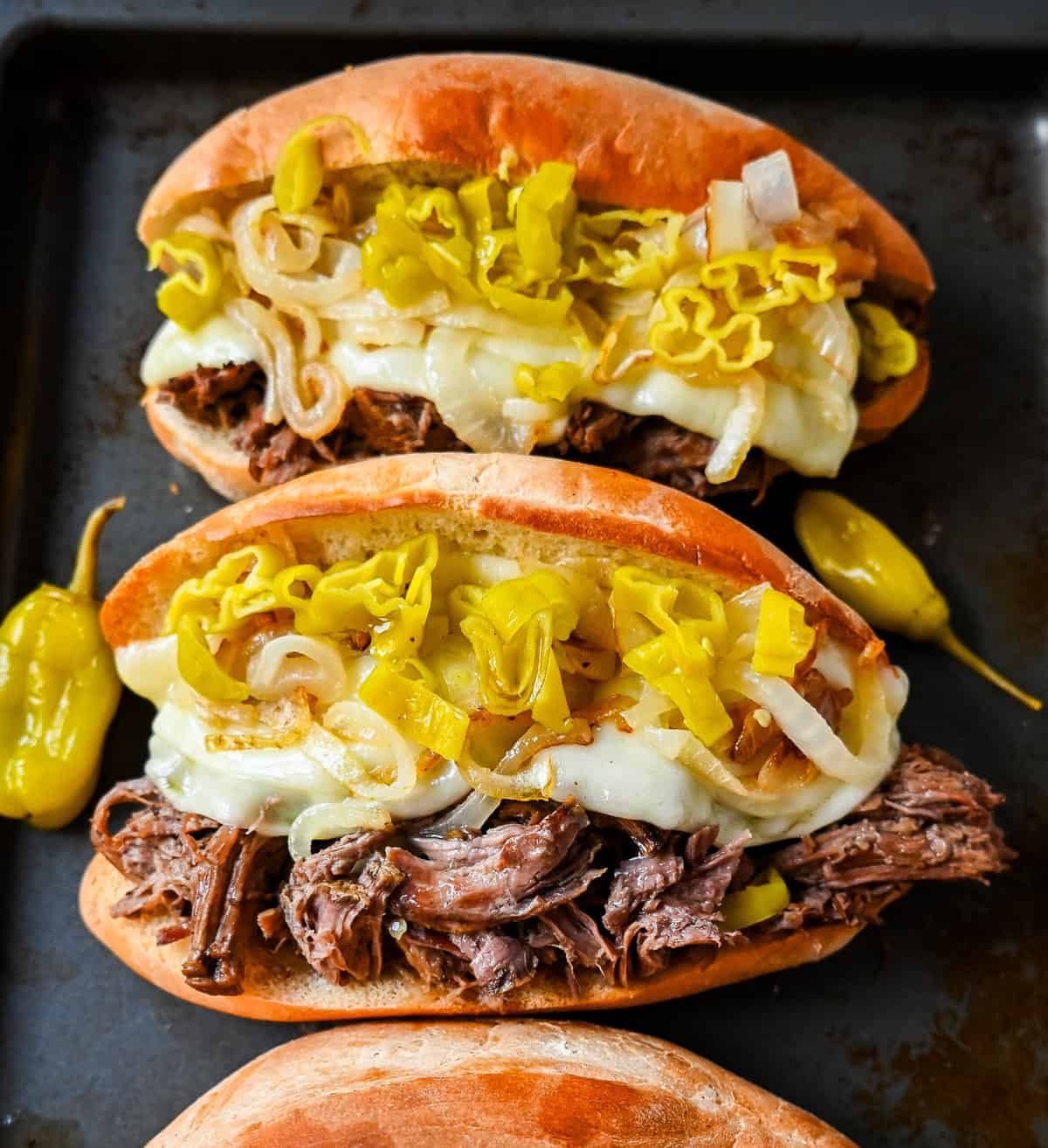 The Best Slow Cooker Italian Beef Sandwiches. These Crockpot Italian Beef Sandwiches are made with flavorful slow cooked beef, shredded to perfection, and placed in a buttered bun, and topped with melted provolone cheese, caramelized onions, and pepperoncini peppers.