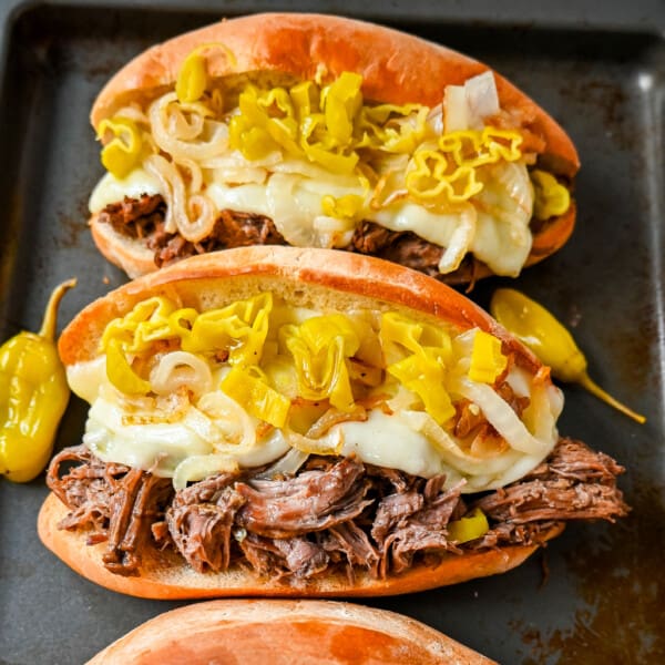 The Best Slow Cooker Italian Beef Sandwiches. These Crockpot Italian Beef Sandwiches are made with flavorful slow cooked beef, shredded to perfection, and placed in a buttered bun, and topped with melted provolone cheese, caramelized onions, and pepperoncini peppers.