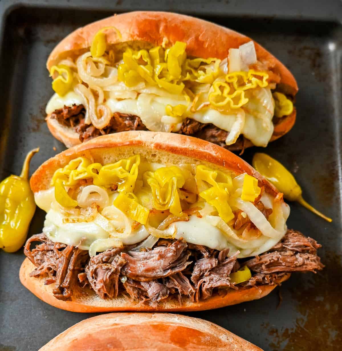 The Best Slow Cooker Italian Beef Sandwiches. These Crockpot Italian Beef Sandwiches are made with flavorful slow cooked beef, shredded to perfection, and placed in a buttered bun, and topped with melted provolone cheese, caramelized onions, and pepperoncini peppers.