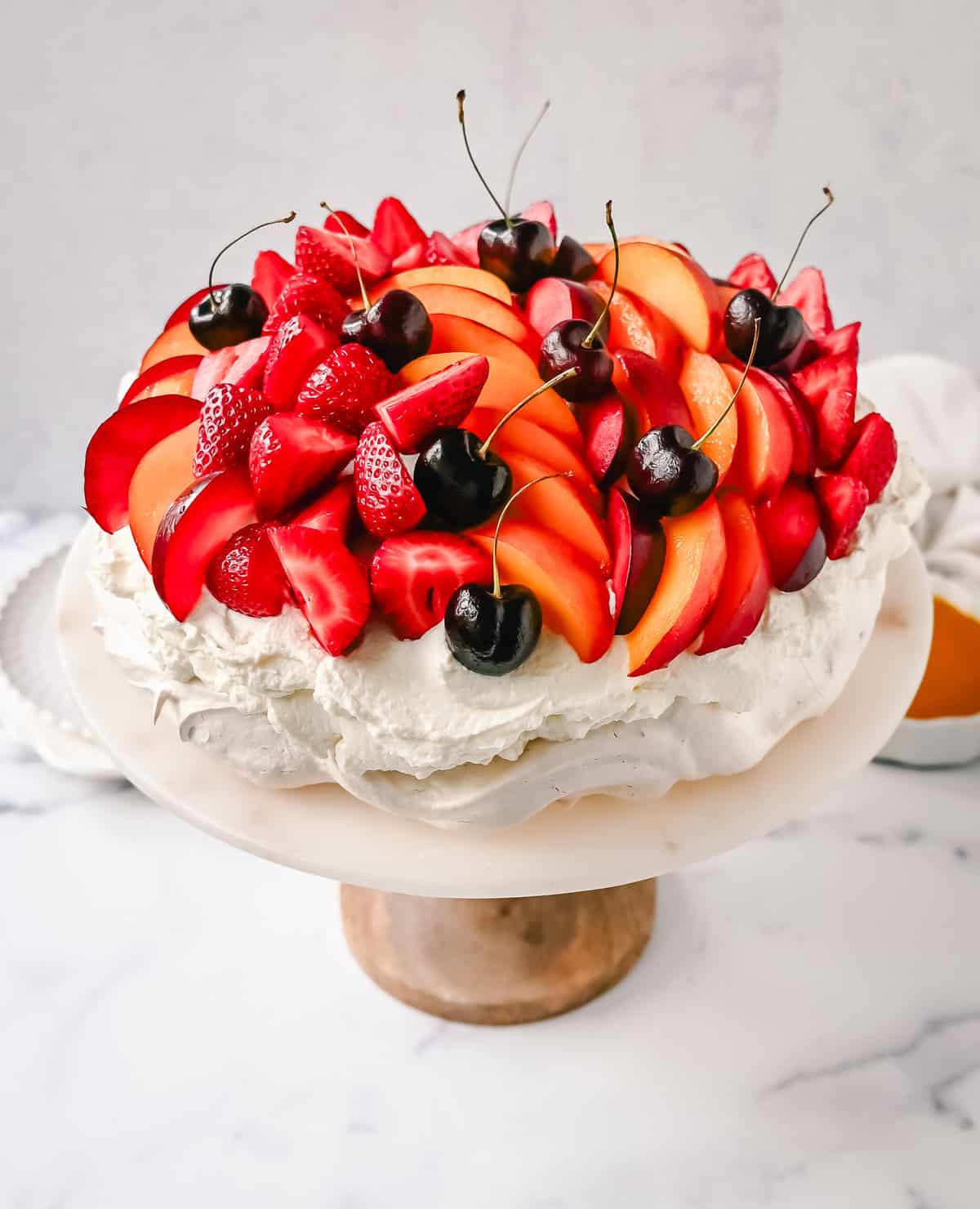 Pavlova. A stunning dessert with a crisp, crunchy outer shell with a soft, marshmallow-like center. Topped with fresh whipped cream and fresh fruit. It is a beautiful and delicious dessert to wow a crowd!