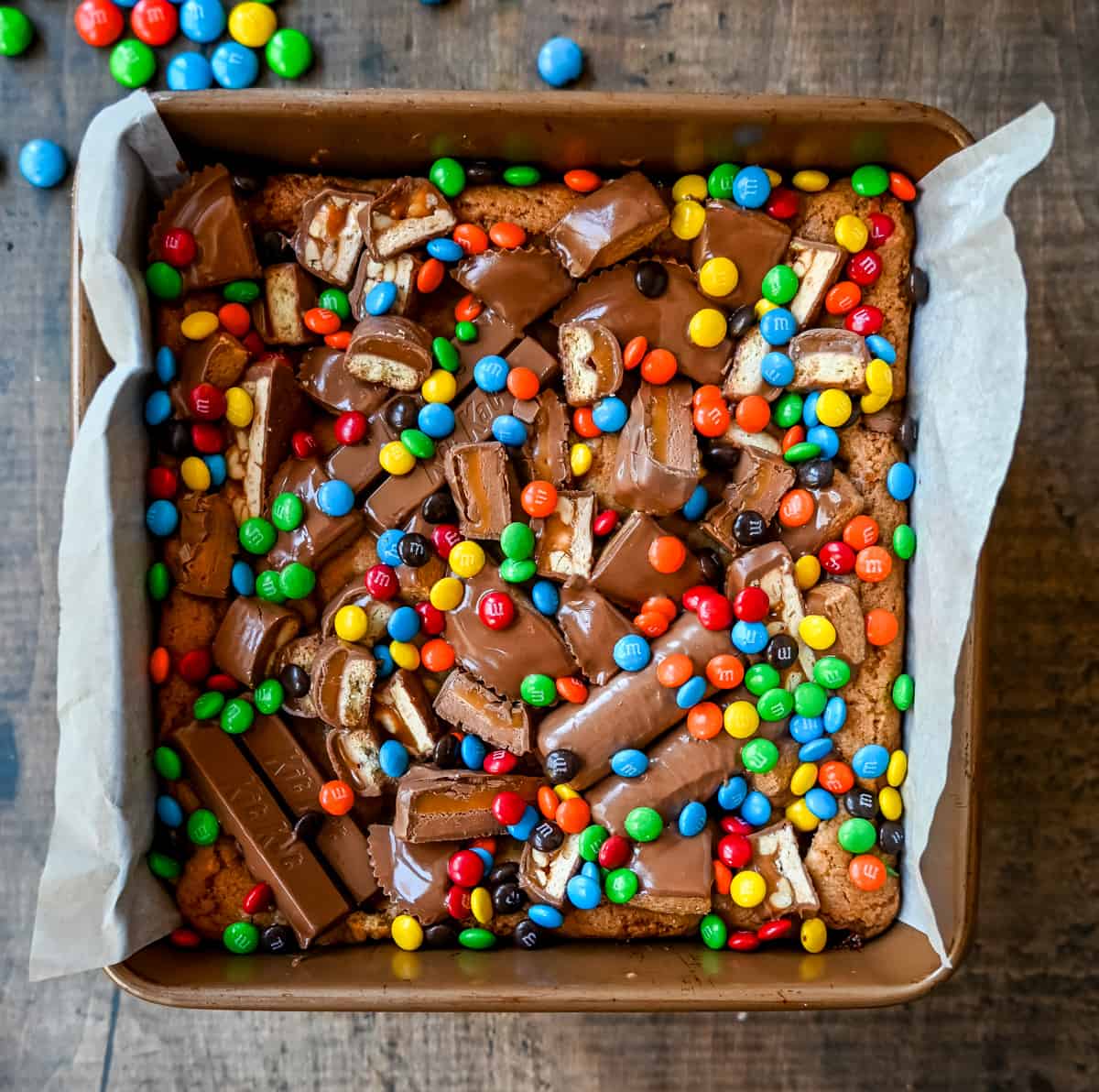 An ooey gooey cookie bar topped with an assortment of candy bars. The perfect candy bar blondie dessert to make with Halloween candy. 