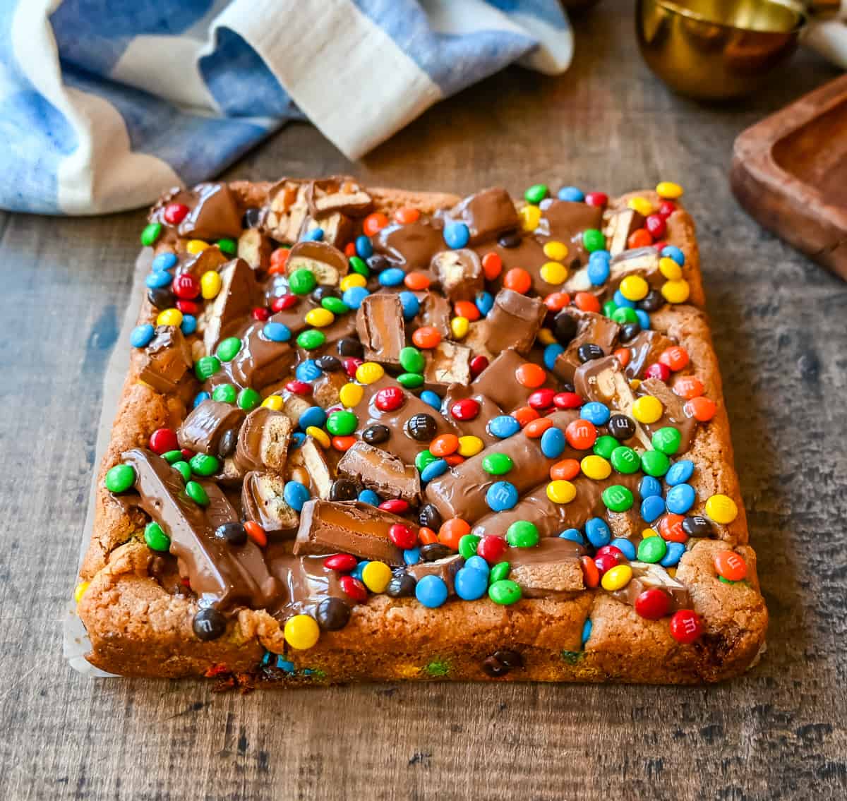 An ooey gooey cookie bar topped with an assortment of candy bars. The perfect candy bar blondie dessert to make with Halloween candy. 