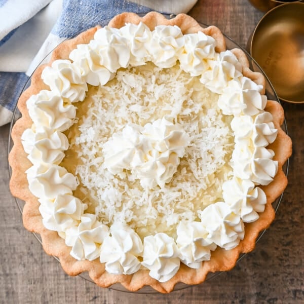 This Coconut Cream Pie is made with a homemade coconut custard filling in a buttery pie crust topped with fresh whipped cream and toasted coconut. This is the famous Dahlia Bakery's secret coconut cream pie recipe.