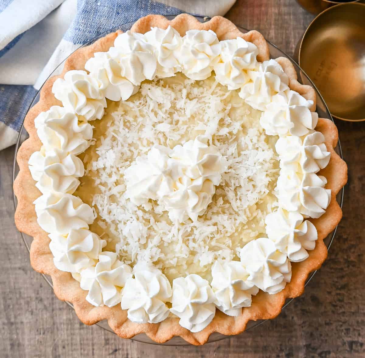 This Coconut Cream Pie is made with a homemade coconut custard filling in a buttery pie crust topped with fresh whipped cream and toasted coconut. This is the famous Dahlia Bakery's secret coconut cream pie recipe.