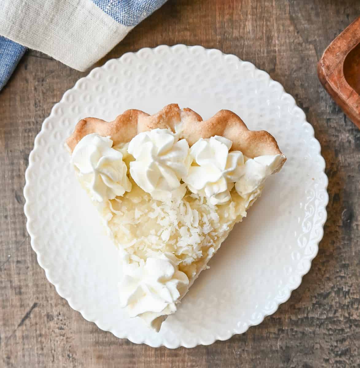 This Coconut Cream Pie is made with a homemade coconut custard filling in a buttery pie crust topped with fresh whipped cream and toasted coconut. This is the famous Dahlia Bakery's secret coconut cream pie recipe.