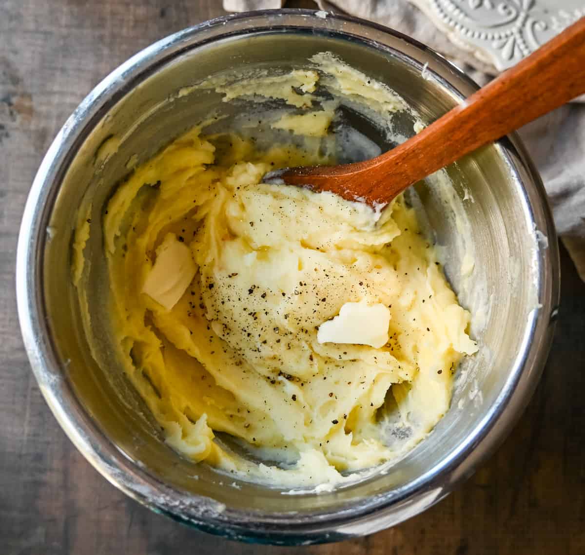 Mashing parmesan roasted garlic mashed potatoes in bowl