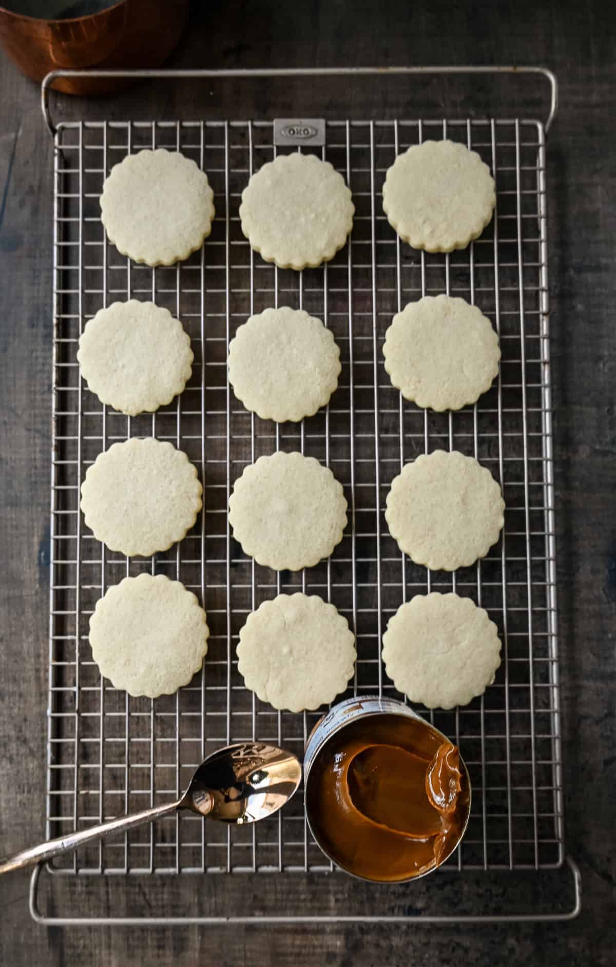 Alfajores baked and spreading dulce de leche on cookie