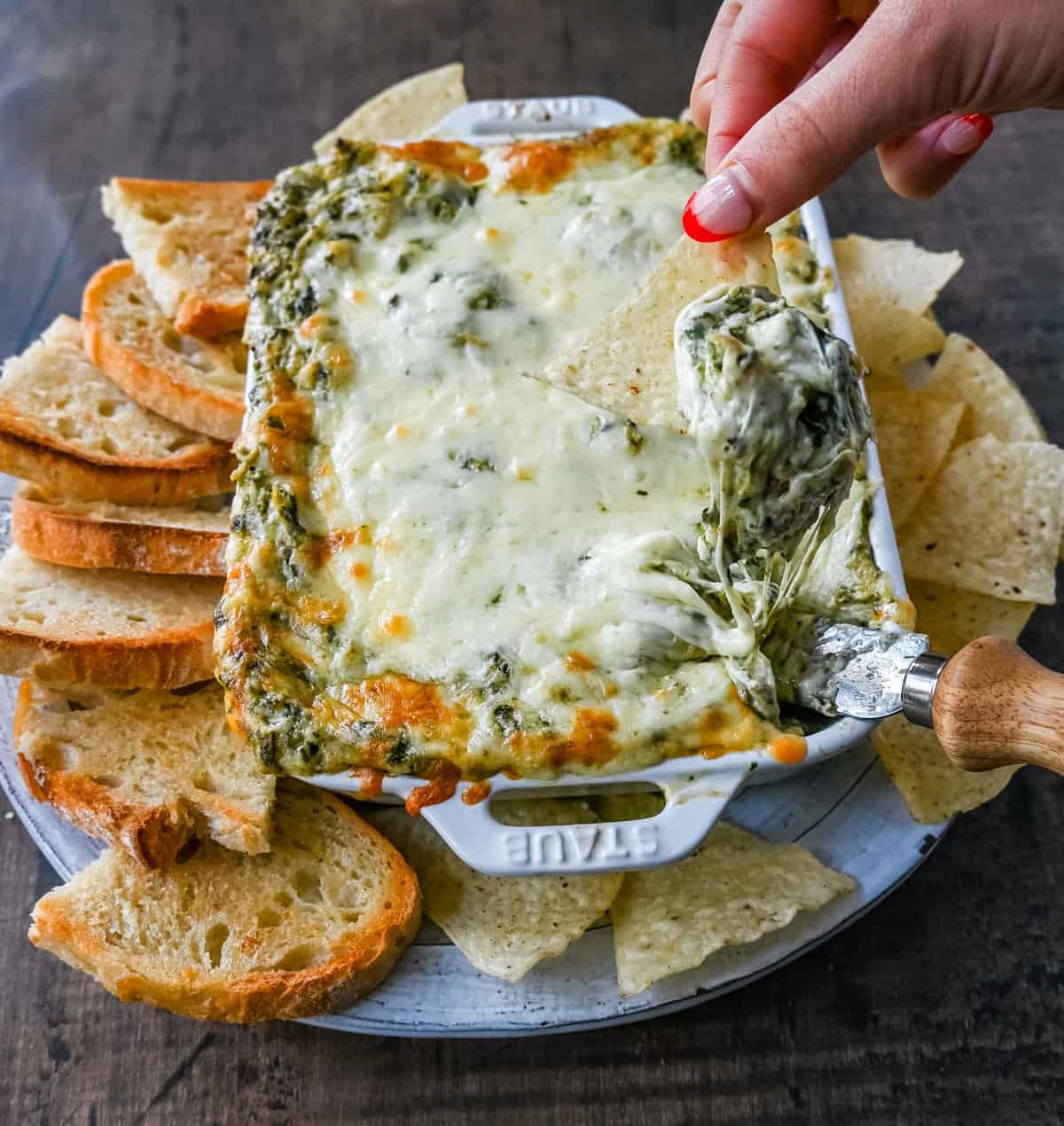 Hot Spinach Artichoke Dip. This easy spinach artichoke dip is creamy and cheesy and always a crowd pleaser! This warm spinach artichoke dip is served with tortilla chips, crackers, or bread for the perfect dip recipe.