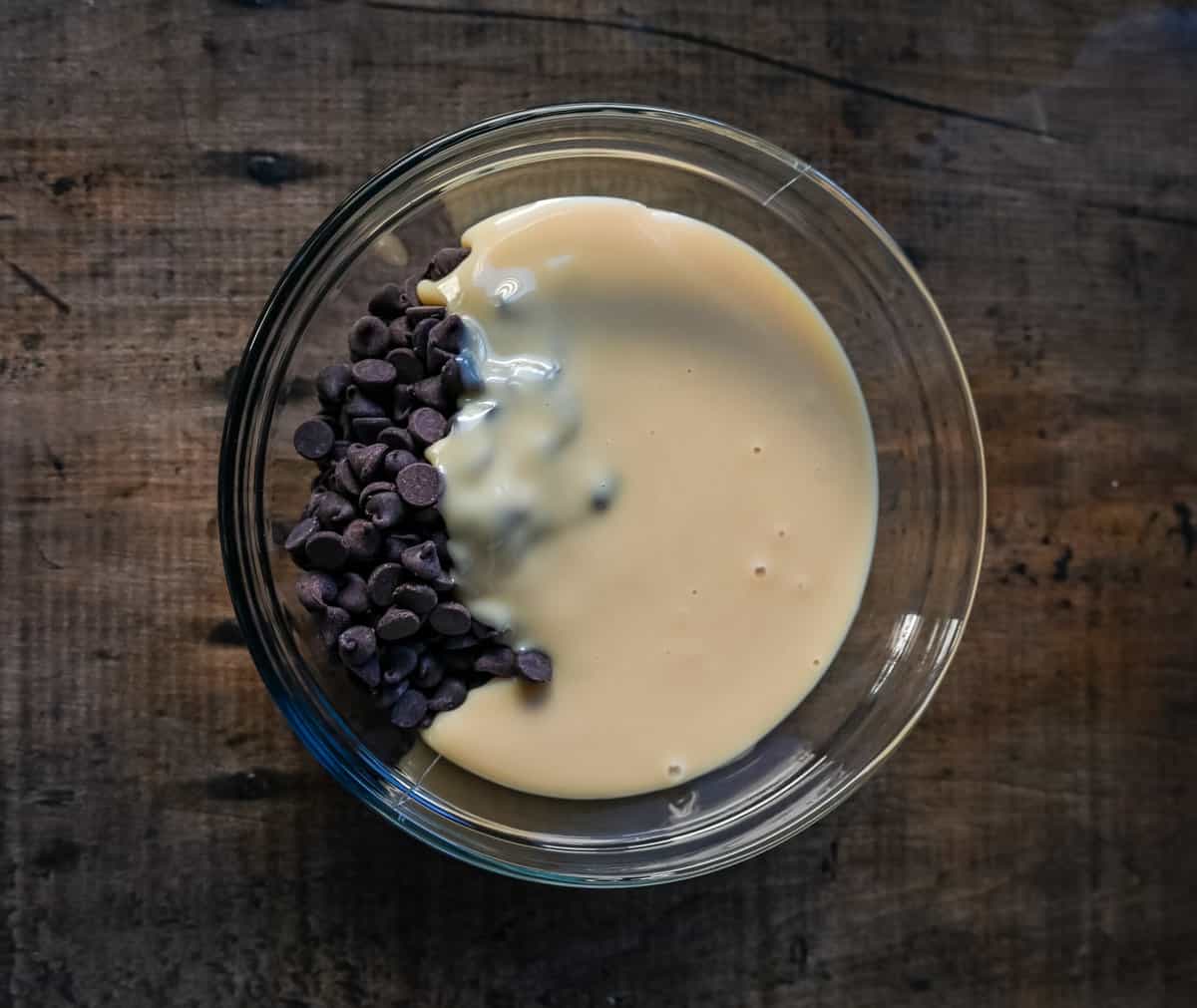 Mixing sweetened condensed milk and chocolate together in microwave safe bowl.