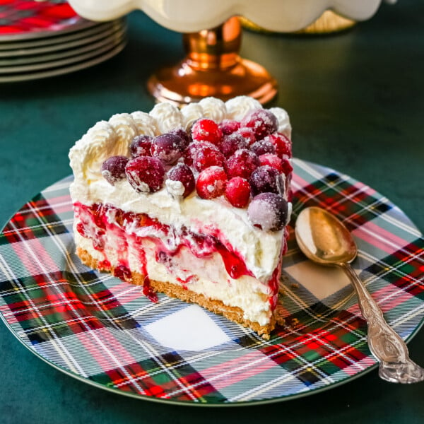 No-Bake Cranberry White Chocolate Cheesecake. This is a beautiful Christmas Cranberry Cheesecake perfect for the holidays. This no-bake white chocolate cheesecake has a graham cracker crust, white chocolate cream cheese filling, topped with homemade cranberry jam, sugared cranberries, and whipped cream.