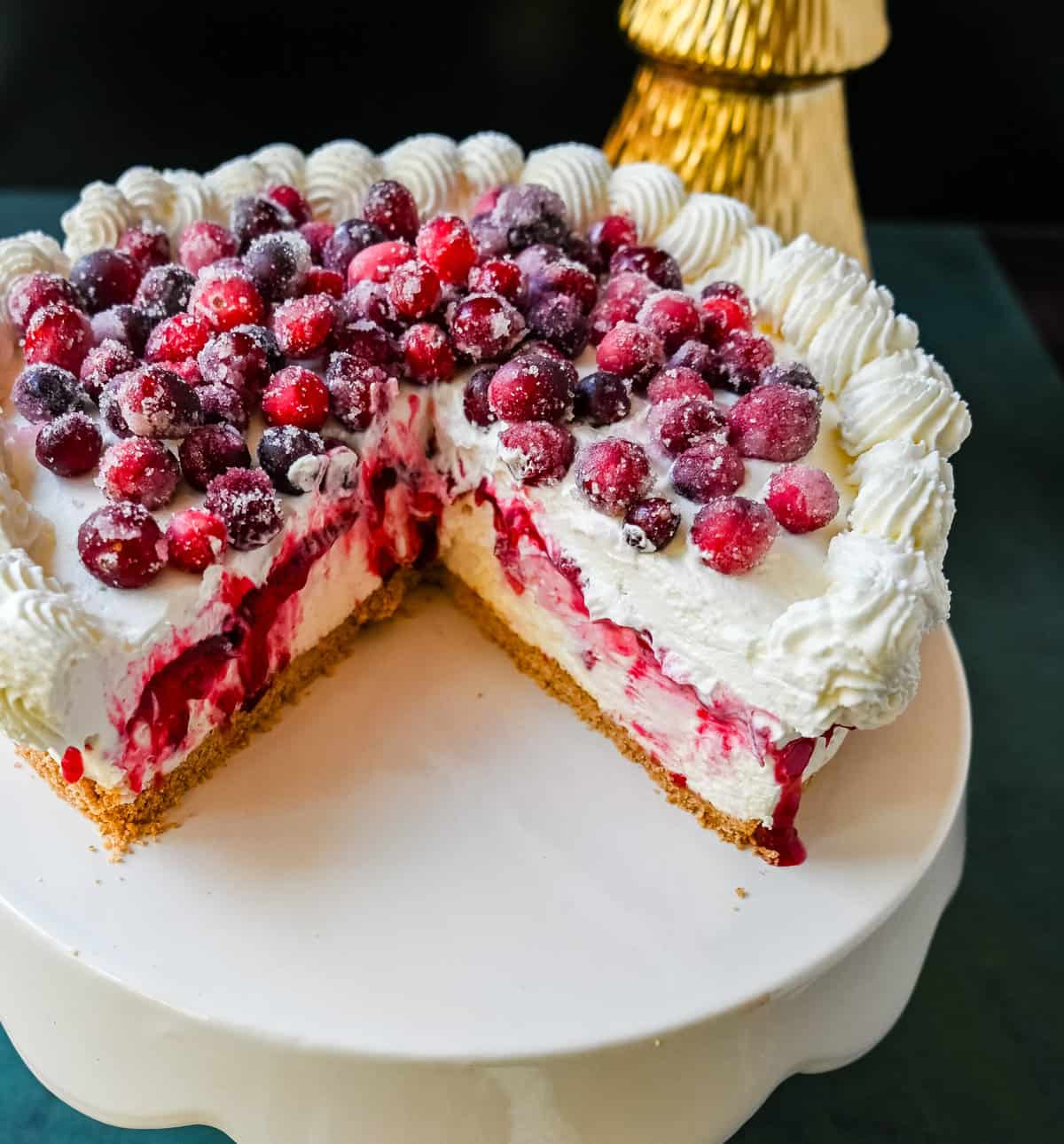 No-Bake Cranberry White Chocolate Cheesecake. This is a beautiful Christmas Cranberry Cheesecake perfect for the holidays. This no-bake white chocolate cheesecake has a graham cracker crust, white chocolate cream cheese filling, topped with homemade cranberry jam, sugared cranberries, and whipped cream.