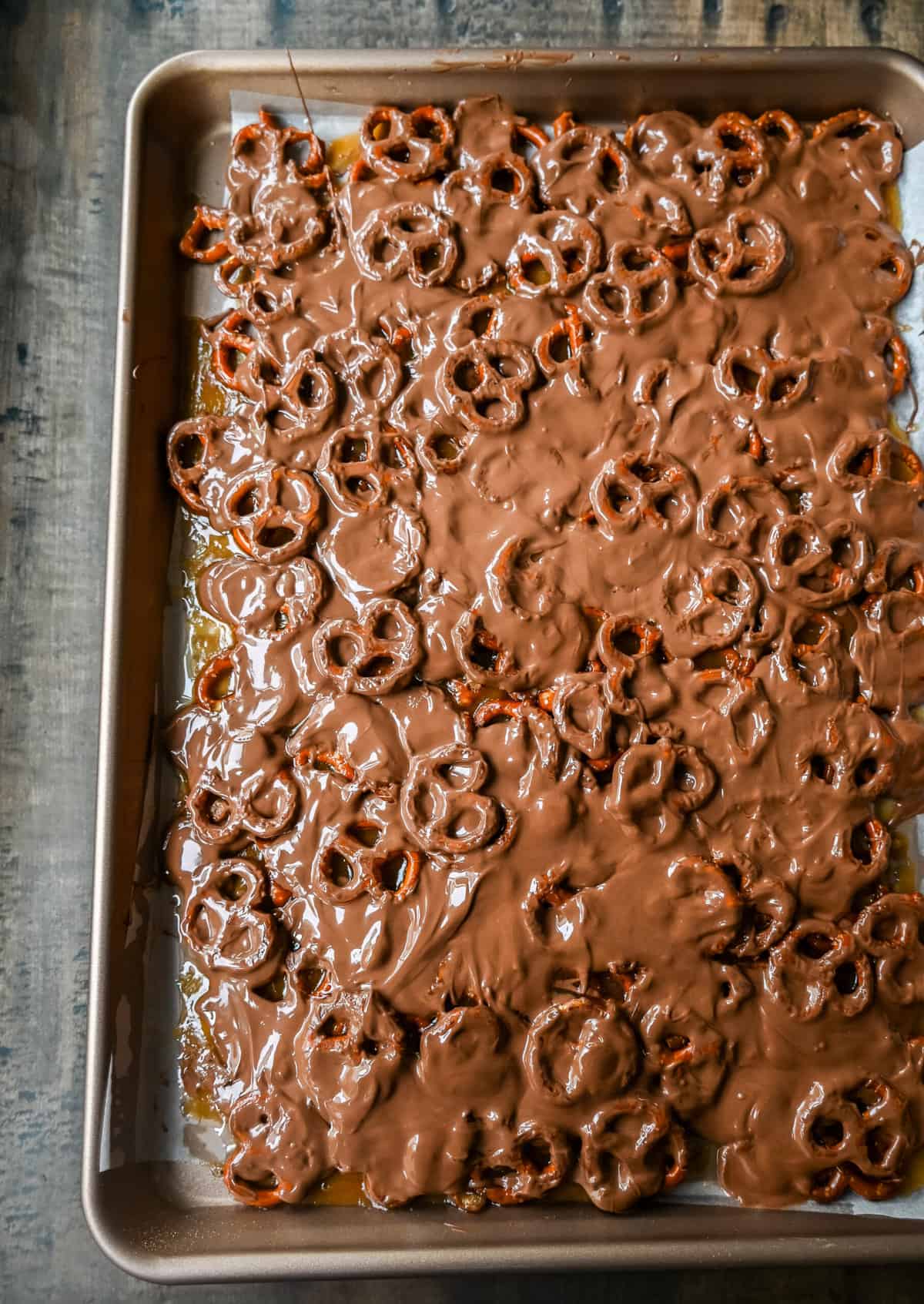 Toffee Pretzel Christmas Crack pouring chocolate over toffee pretzels