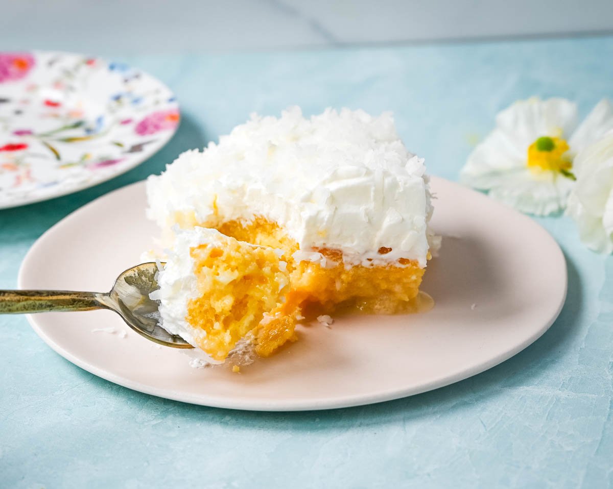 This Coconut Poke Cake is made with a baked cake mix and filled with cream of coconut and sweetened condensed milk and topped with sweet whipped cream and coconut. This Coconut Tres Leches Cake is so easy to make and is perfect for potlucks and parties.