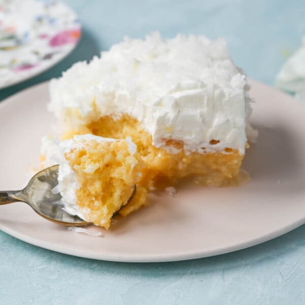 This Coconut Poke Cake is made with a baked cake mix and filled with cream of coconut and sweetened condensed milk and topped with sweet whipped cream and coconut. This Coconut Tres Leches Cake is so easy to make and is perfect for potlucks and parties.