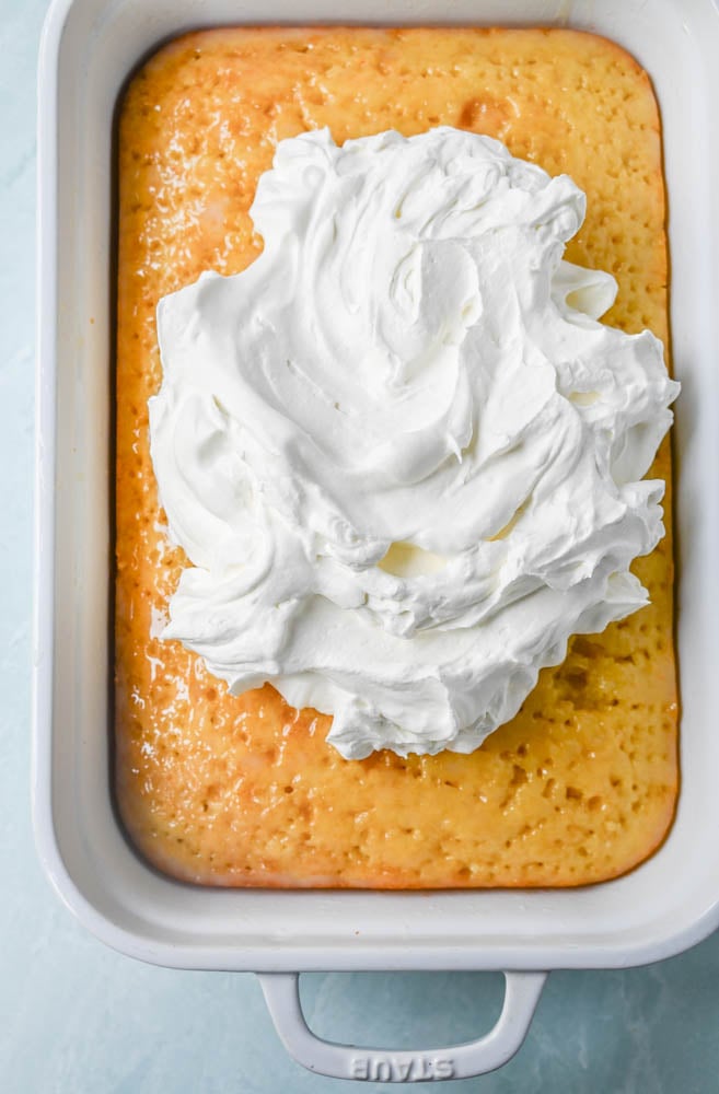 This Coconut Poke Cake is made with a baked cake mix and filled with cream of coconut and sweetened condensed milk and topped with sweet whipped cream and coconut. This Coconut Tres Leches Cake is so easy to make and is perfect for potlucks and parties.