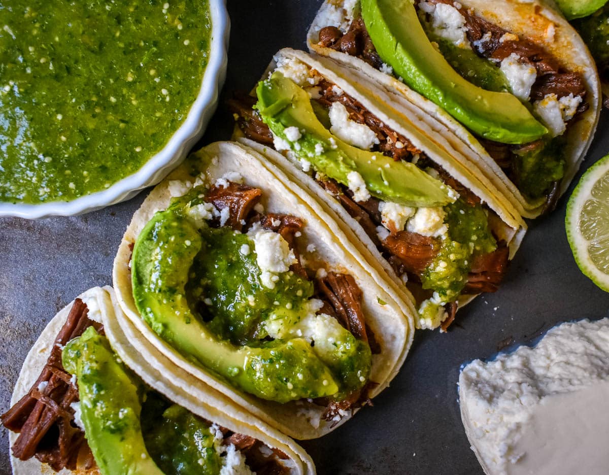 Slow Cooker Beef Barbacoa Tacos with Salsa Verde. These Barbacoa Beef Tacos with Tomatillo Salsa are made with slow cooked, Mexican spiced beef inside fresh corn tortillas and topped with homemade salsa verde, Mexican cheese, and fresh avocado. An easy and flavorful beef tacos recipe!