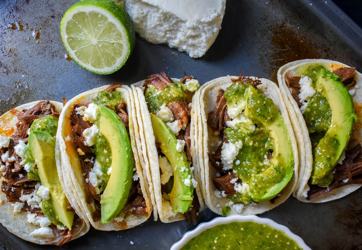 Slow Cooker Beef Barbacoa Tacos with Salsa Verde. These Barbacoa Beef Tacos with Tomatillo Salsa are made with slow cooked, Mexican spiced beef inside fresh corn tortillas and topped with homemade salsa verde, Mexican cheese, and fresh avocado. An easy and flavorful beef tacos recipe!