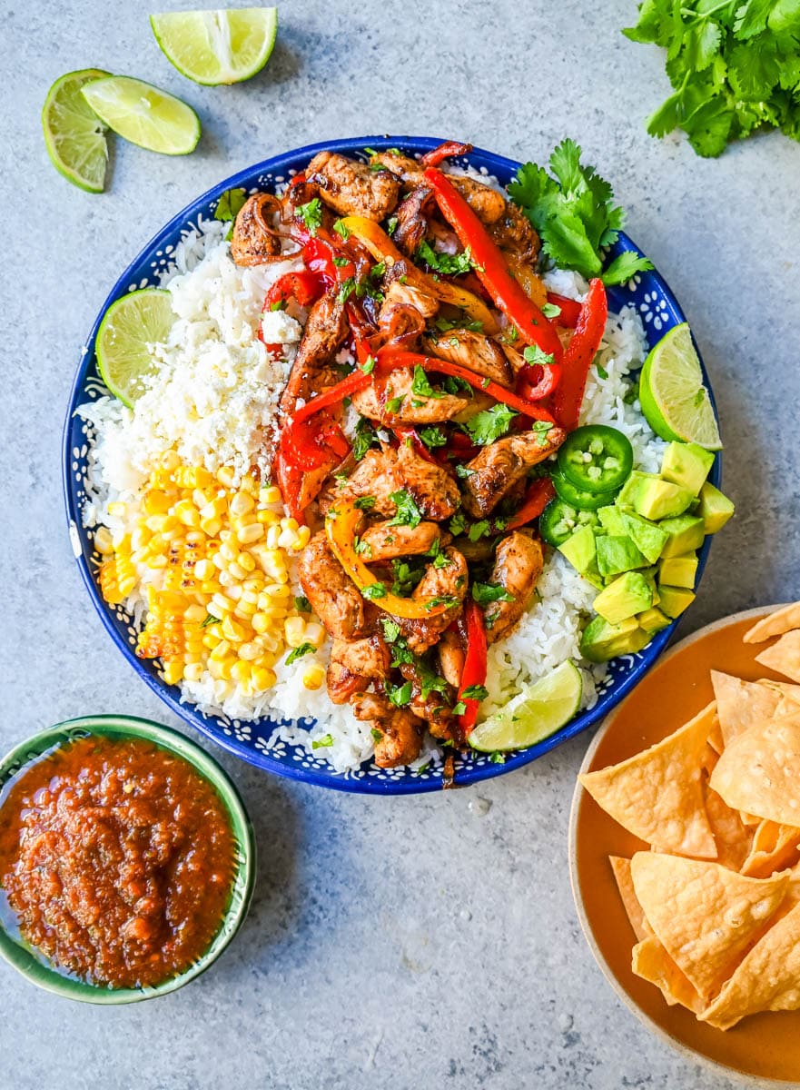 Chicken Fajita Bowl. Juicy, flavorful chicken fajitas in a bowl with rice, beans, charred corn, guacamole, salsa, and fresh cilantro. The flavors of chicken fajitas without the tortillas!