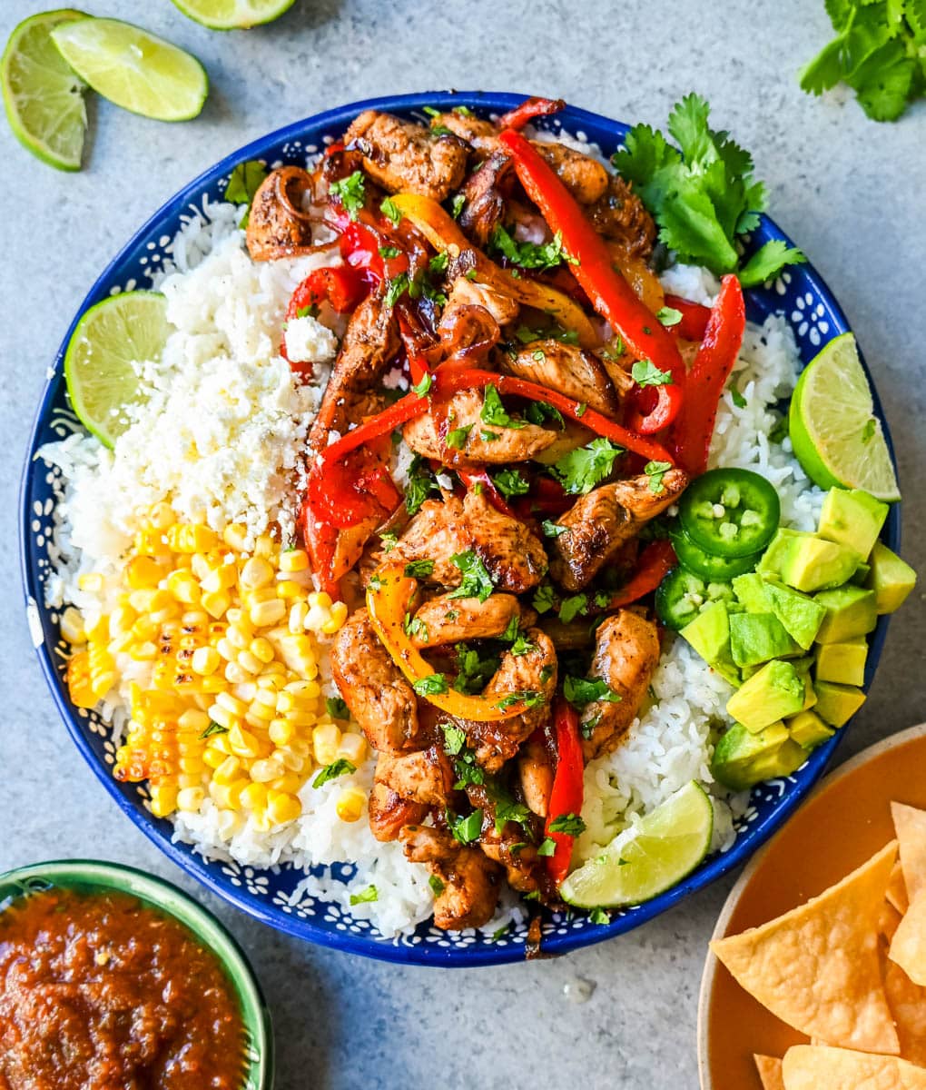 Chicken Fajita Bowl. Juicy, flavorful chicken fajitas in a bowl with rice, beans, charred corn, guacamole, salsa, and fresh cilantro. The flavors of chicken fajitas without the tortillas!