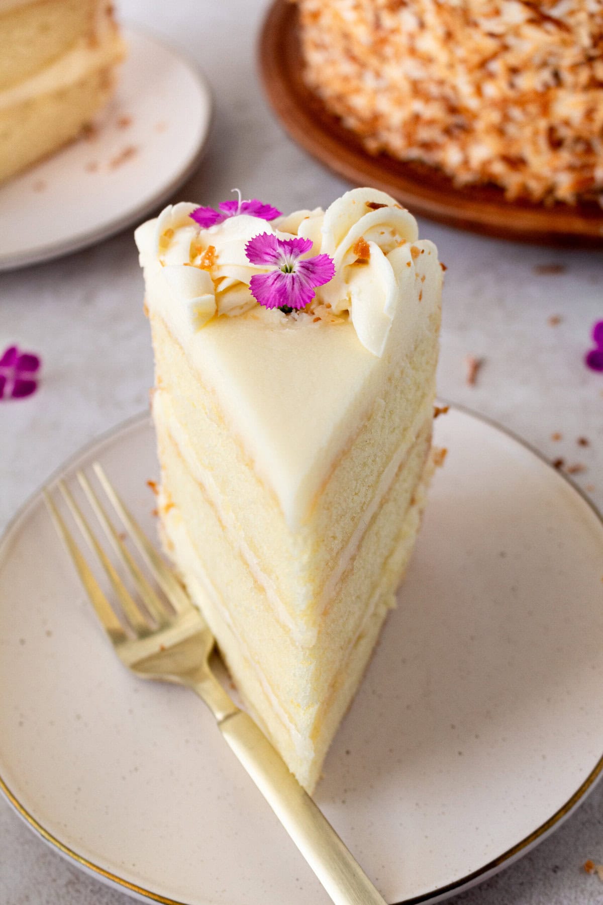 This homemade, moist coconut cake with coconut cream cheese frosting is the best coconut cake recipe. It is made with sweet cream butter, coconut milk, buttermilk, coconut pudding mix, and cake flour to make it extra tender. The coconut cream cheese frosting puts it over the top!
