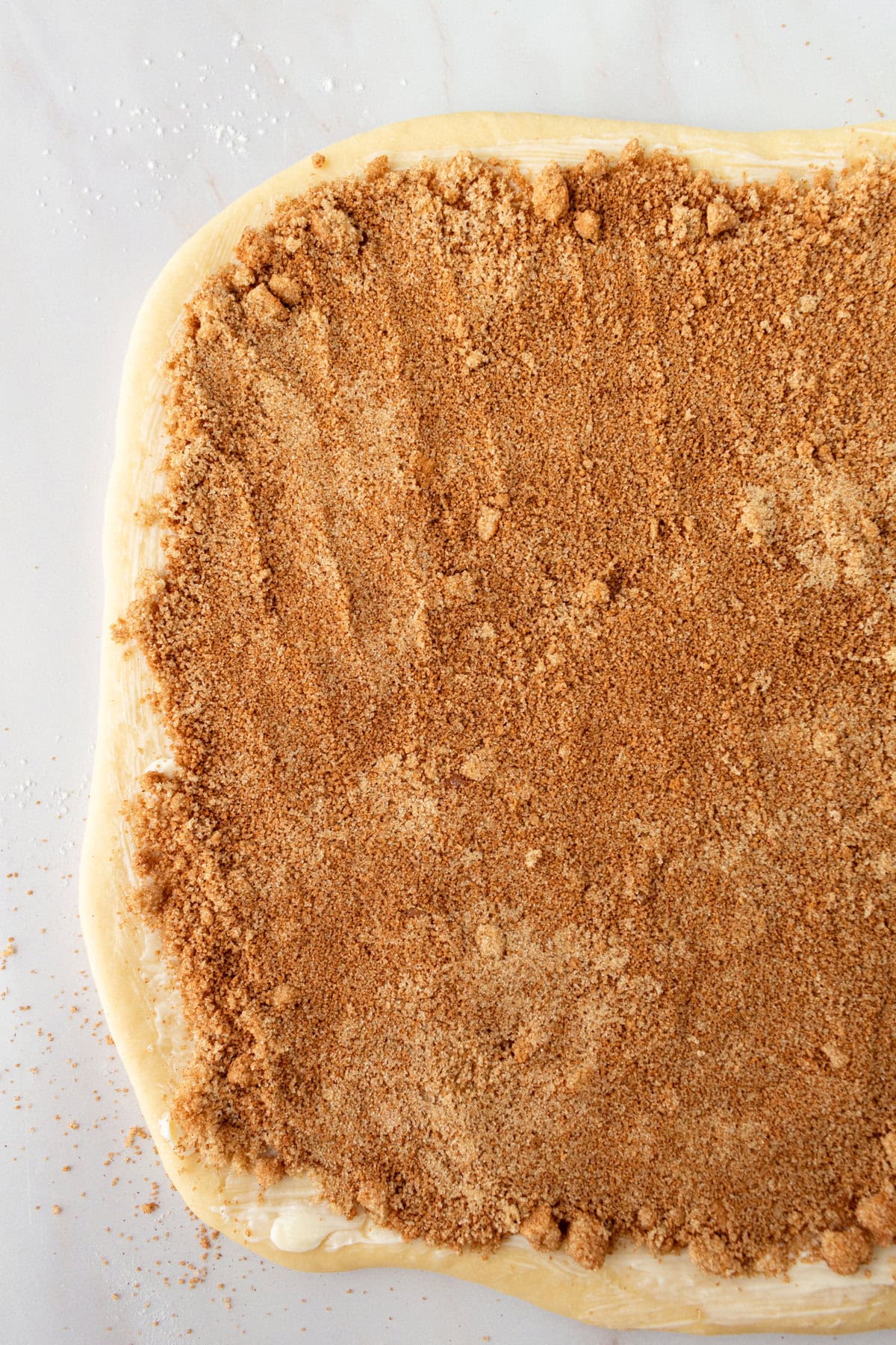 Roll out cinnamon roll dough dough and spread with butter, cinnamon, and sugar.