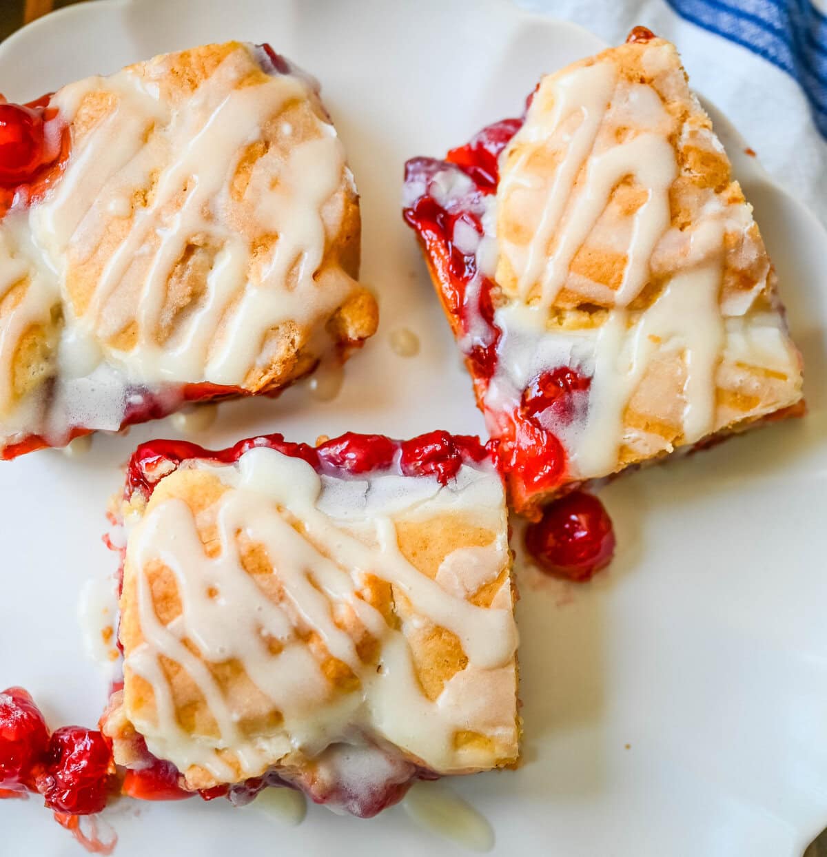 If you're craving cherry pie but want an easier recipe, these Cherry Pie Bars with a Cookie Crust are the answer. With a soft, buttery crust on the bottom, a layer of sweet cherry pie filling, and golden cookie crumbles on top, and a drizzle of icing. These may be even better than cherry pie without all of the work.
