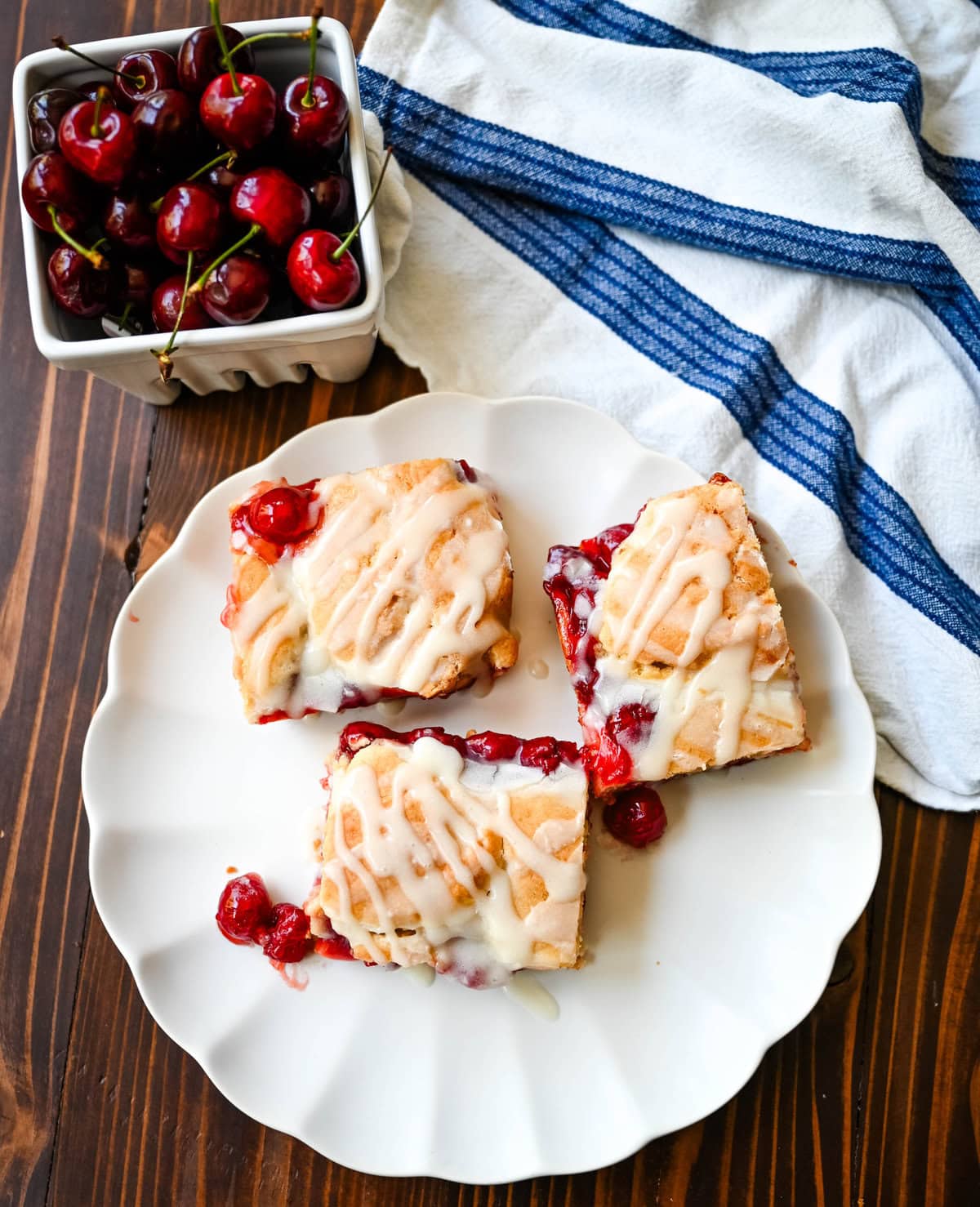 If you're craving cherry pie but want an easier recipe, these Cherry Pie Bars with a Cookie Crust are the answer. With a soft, buttery crust on the bottom, a layer of sweet cherry pie filling, and golden cookie crumbles on top, and a drizzle of icing. These may be even better than cherry pie without all of the work.