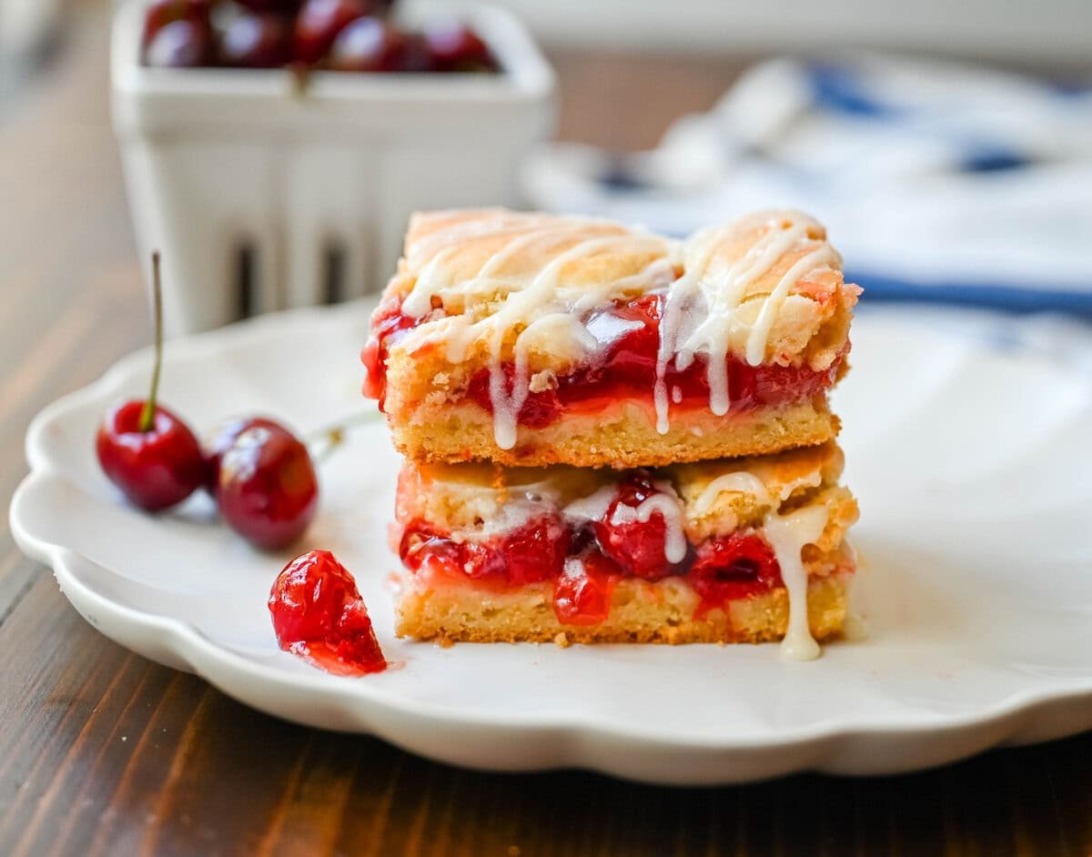If you're craving cherry pie but want an easier recipe, these Cherry Pie Bars with a Cookie Crust are the answer. With a soft, buttery crust on the bottom, a layer of sweet cherry pie filling, and golden cookie crumbles on top, and a drizzle of icing. These may be even better than cherry pie without all of the work.