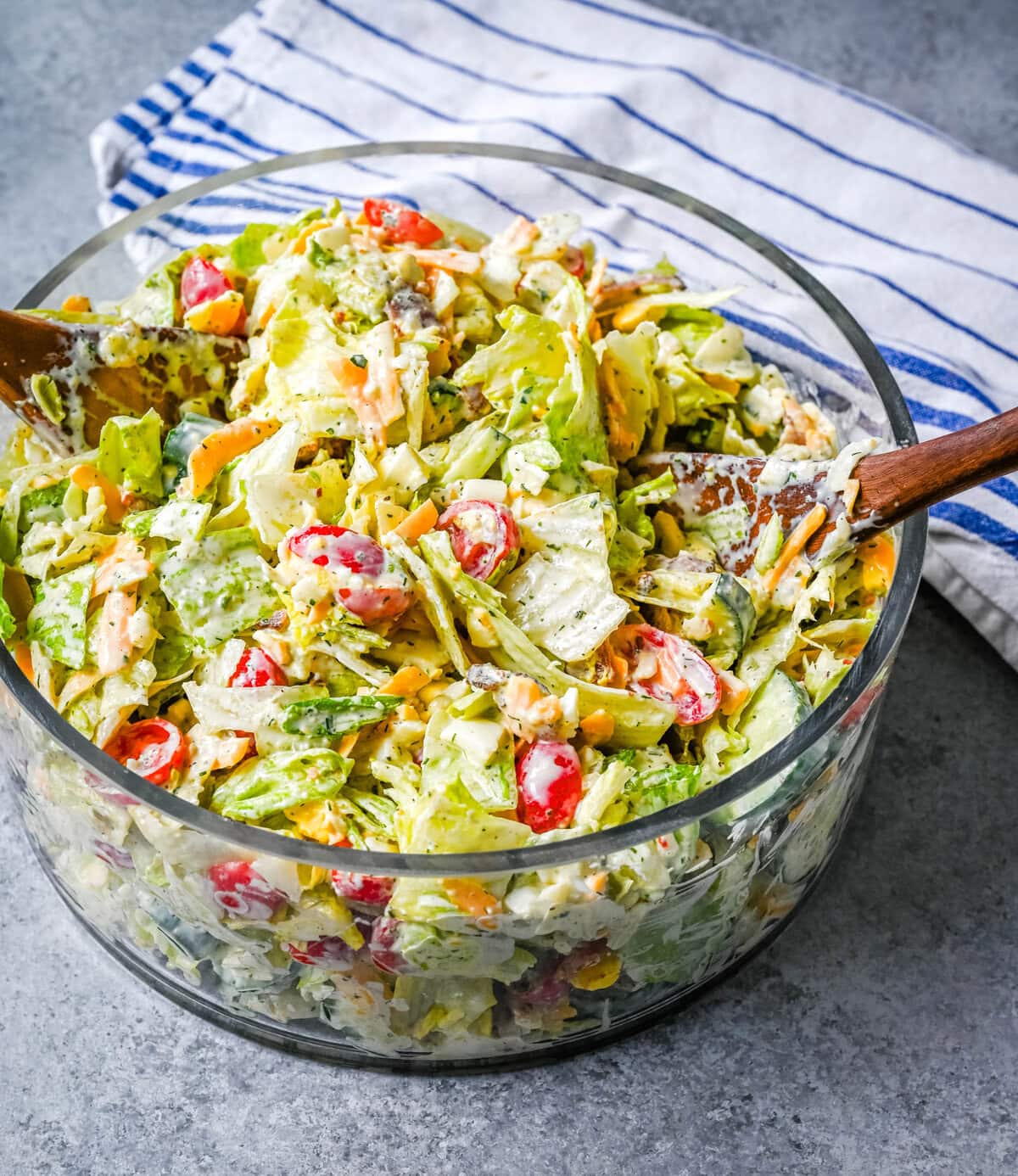 This classic Seven Layer salad is layered with iceberg lettuce, smoky bacon, hard-boiled eggs, sharp cheddar cheese, fresh veggies, and your choice of peas or garbanzo beans, plus creamy avocado. It's the ultimate make-ahead side dish, perfect for BBQs or family dinners. This easy, crowd-pleasing 7 Layer Salad is topped with a generous drizzle of homemade ranch dressing. This easy, crowd-pleasing layered salad is a beautiful, delicious side dish!