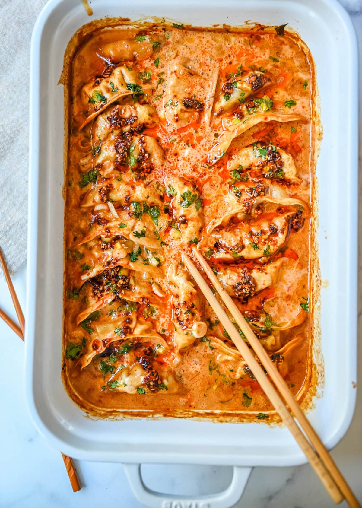 These viral baked dumplings from TikTok are the ultimate easy dinner hack! Crispy dumplings are baked in a creamy coconut curry sauce and topped with cilantro, chili crunch oil, and sesame seeds for the perfect mix of flavor and texture. This is an easy sheet pan dinner recipe!
