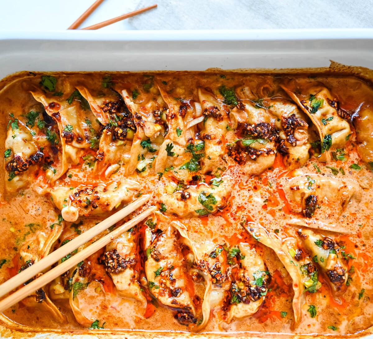 These viral baked dumplings from TikTok are the ultimate easy dinner hack! Crispy dumplings are baked in a creamy coconut curry sauce and topped with cilantro, chili crunch oil, and sesame seeds for the perfect mix of flavor and texture. This is an easy sheet pan dinner recipe!
