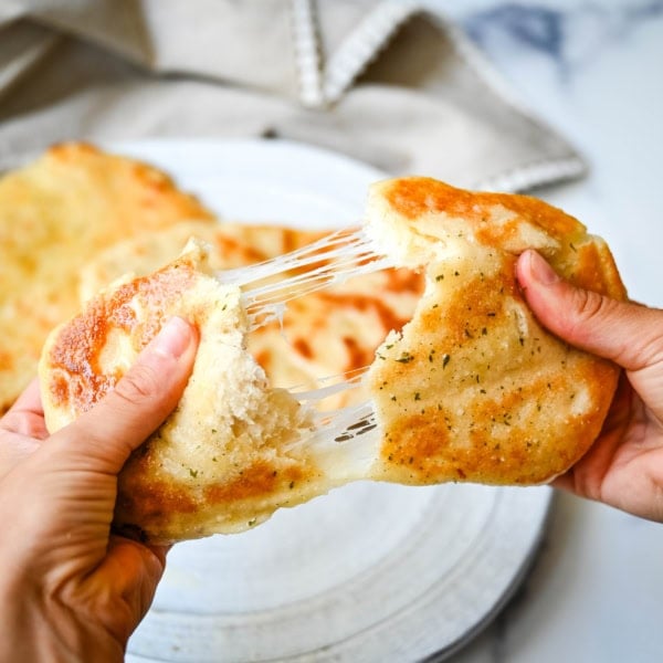 Homemade Cheesy Naan bread stuffed with mozzarella cheese, that is even better than what you find in restaurants. Cheese-stuffed naan is soft, slightly chewy, golden-brown on the outside, fluffy bread layers inside, and melty gooey cheese in the center.