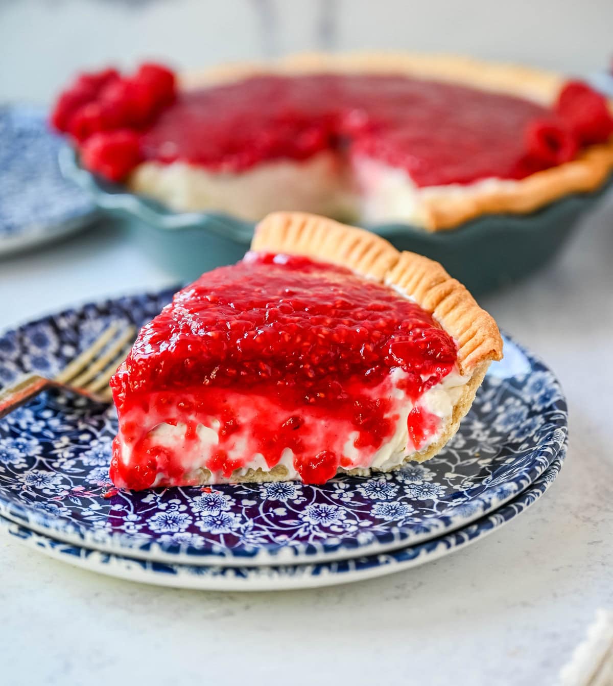 This homemade Raspberry Cream Pie is made with a sweet vanilla cream cheese cheesecake filling topped with a homemade raspberry sauce, all in a buttery, flaky homemade crust. This is a homemade take on the famous Briermere Farms raspberry cream pie and the perfect summer dessert that can be made with fresh or frozen raspberries.